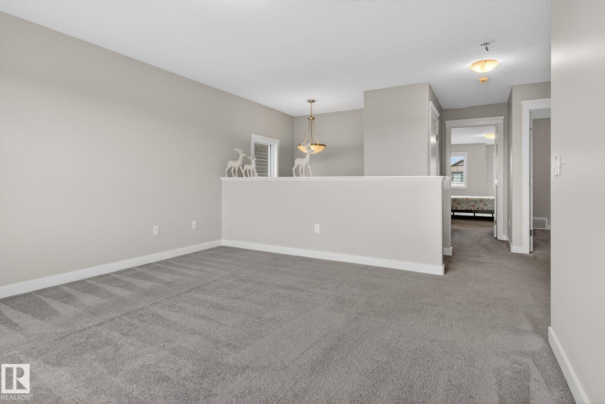 Open loft area with neutral-toned walls and gray carpeting - 7341 Armour Crescent, Edmonton, AB - Indoor Photo Showing Other Room