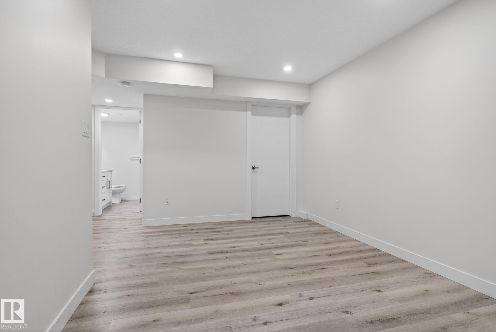 Spacious room featuring wood-finish flooring, recessed lighting, and a neutral color palette - 7341 Armour Crescent, Edmonton, AB - Indoor