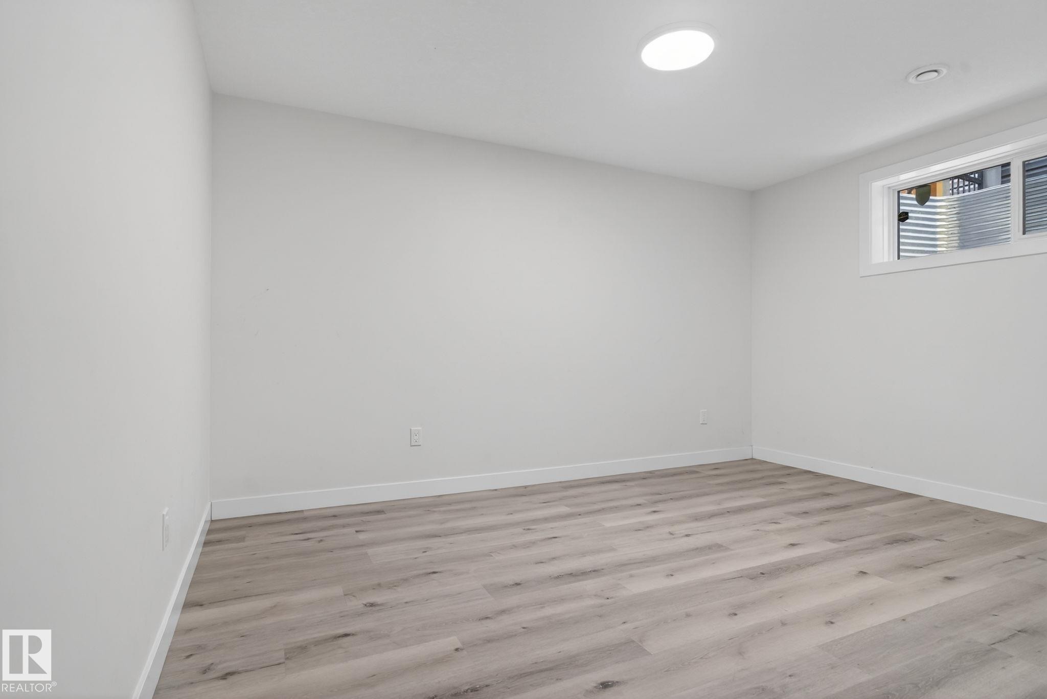 Room featuring wood-finish flooring, white baseboards, and neutral wall paint - 7341 Armour Crescent, Edmonton, AB - Indoor Photo Showing Other Room