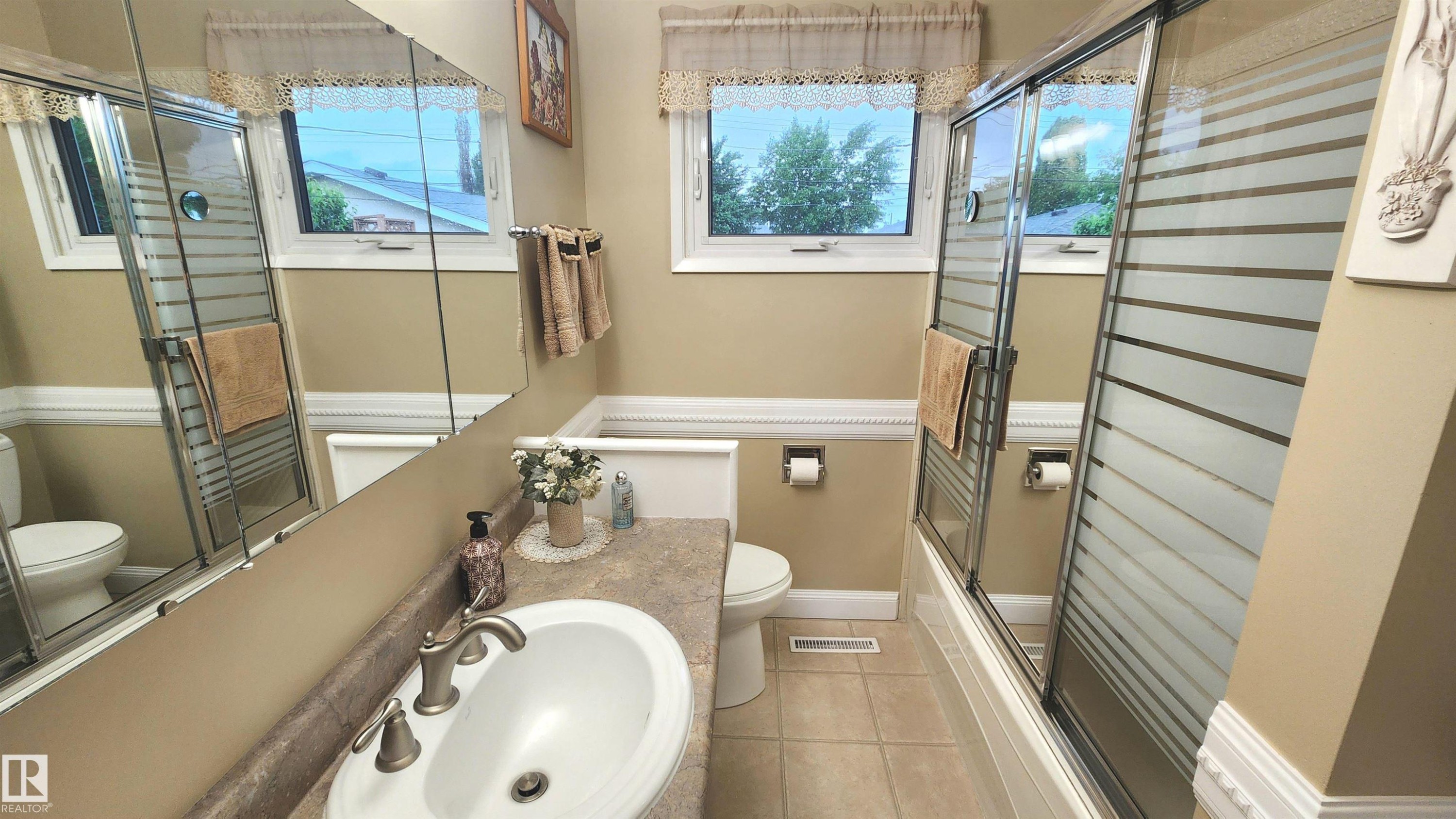 Bathroom featuring a single vanity with a white basin sink, brushed nickel faucet, and a patterned countertop - 13307 Delwood Road, Edmonton, AB