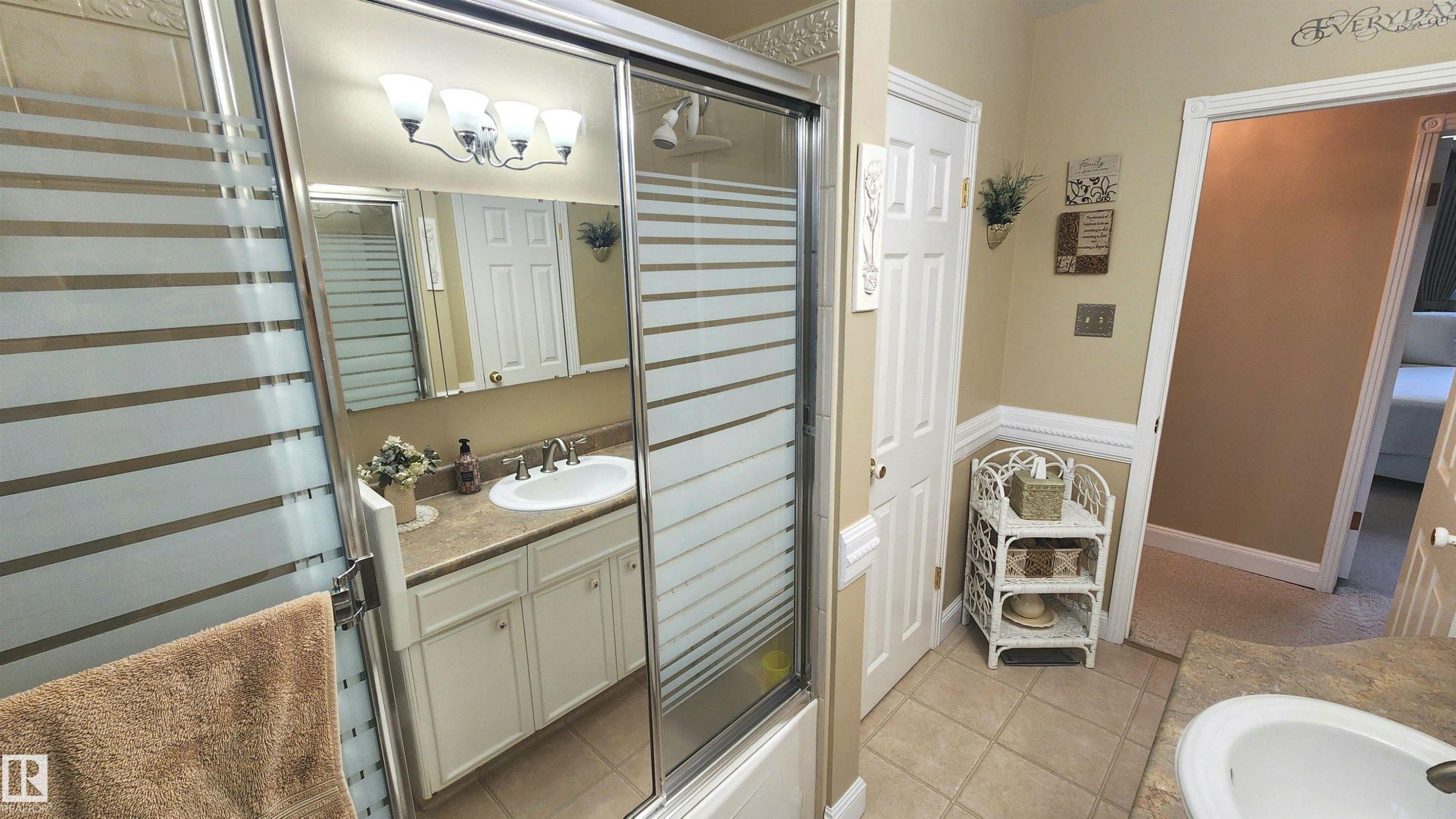 Bathroom featuring a shower with sliding glass doors, a vanity with a drop-in sink and light-toned countertop, and a mirrored medicine cabinet - 13307 Delwood Road, Edmonton, AB