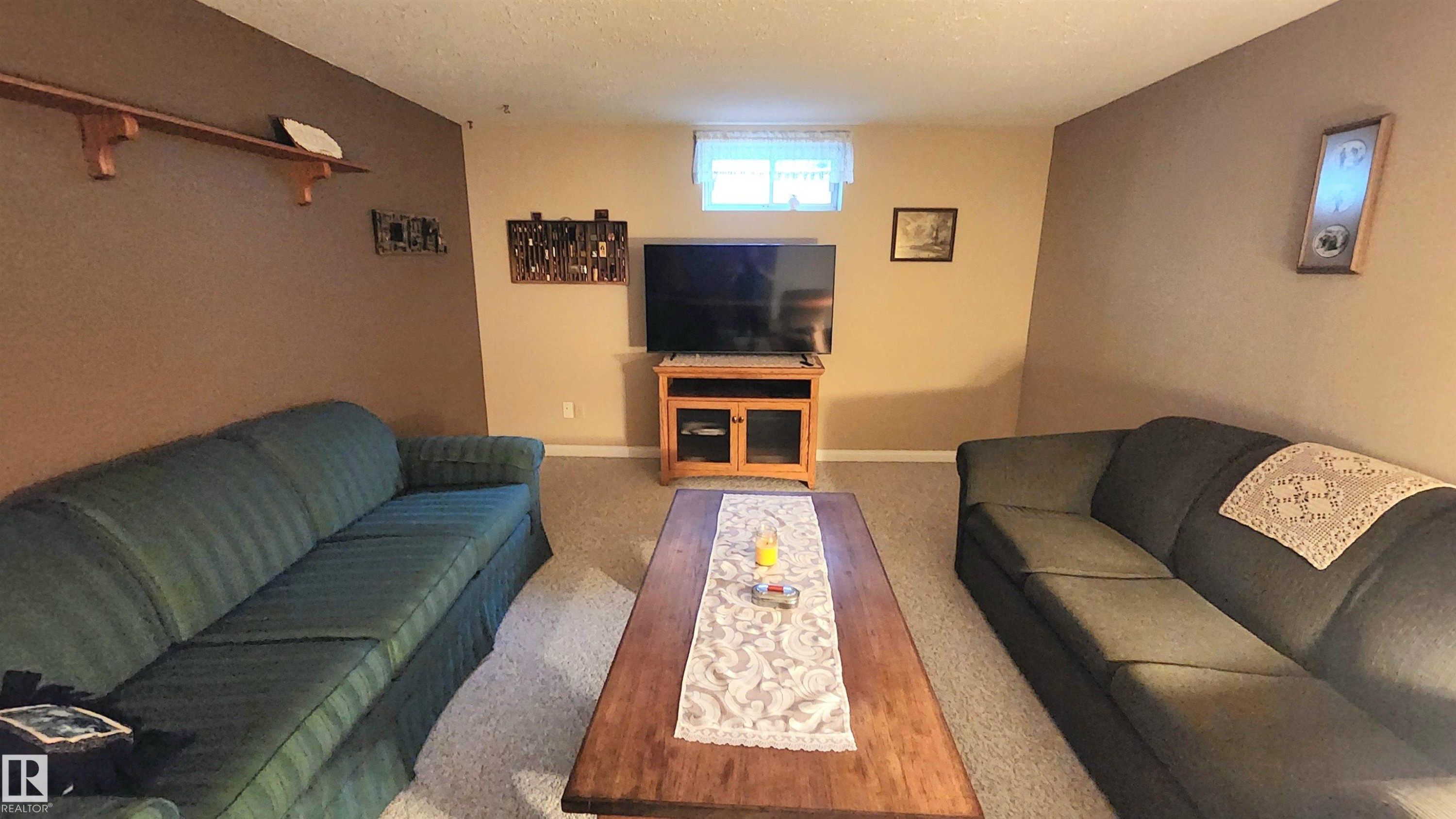 Recreational room featuring carpeted flooring, a built-in wood media console, and a window with white window treatments - 13307 Delwood Road, Edmonton, AB
