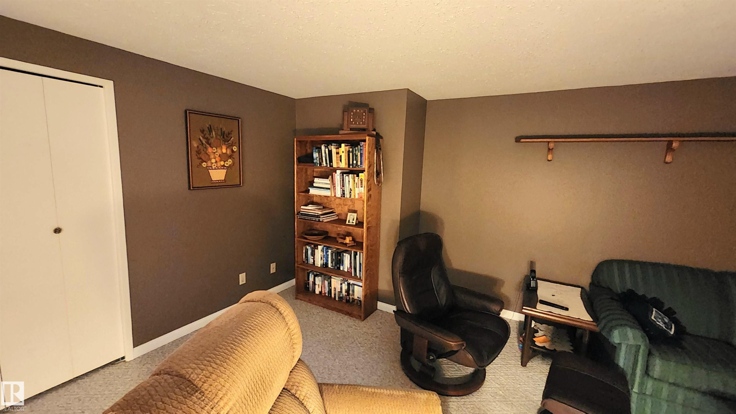 Carpeted room featuring neutral wall tones, white baseboards, and a built-in closet with bi-fold doors - 13307 Delwood Road, Edmonton, AB