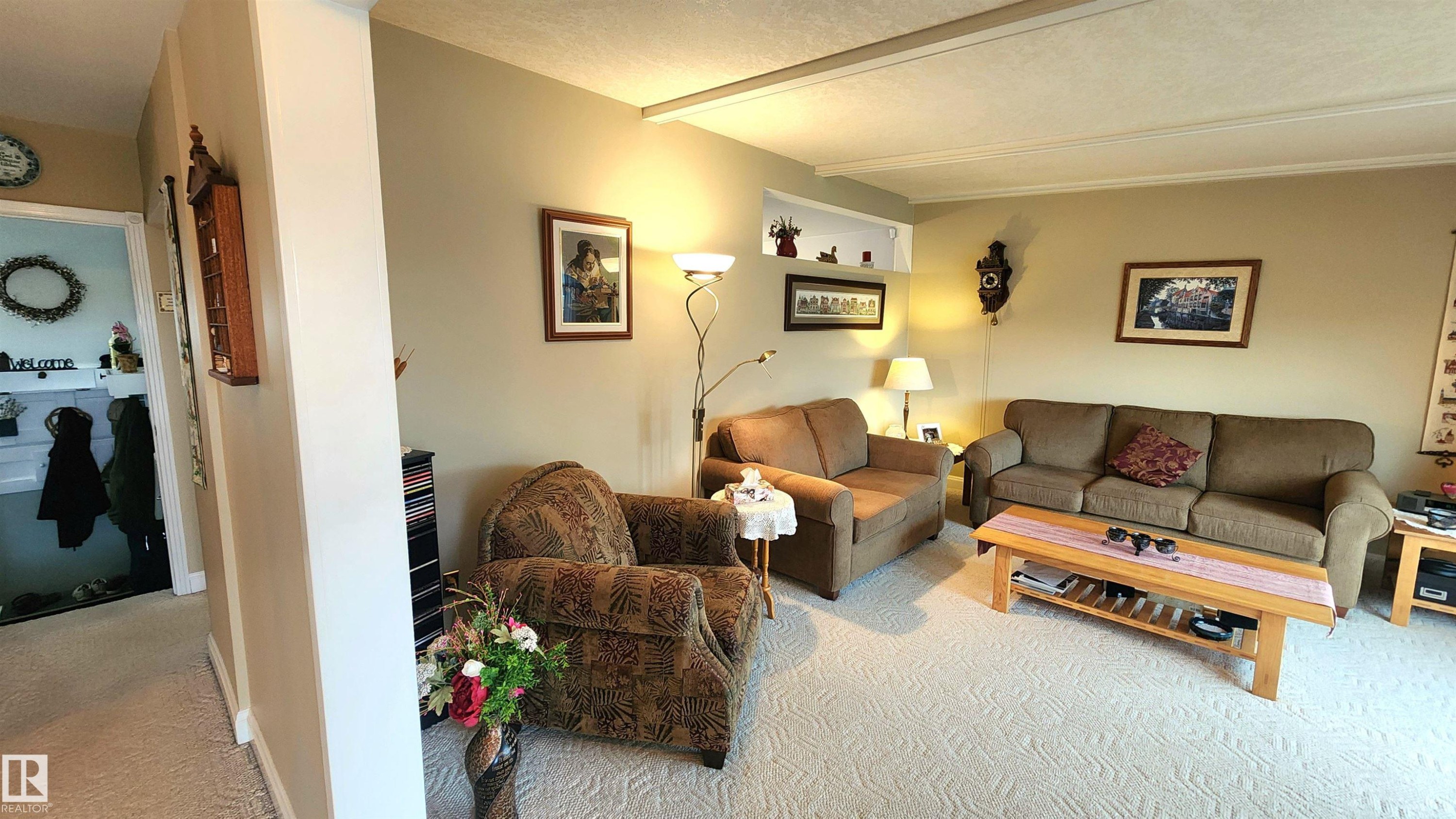 Carpeted living area featuring a built-in recessed wall shelf, neutral wall tones, and overhead lighting - 13307 Delwood Road, Edmonton, AB