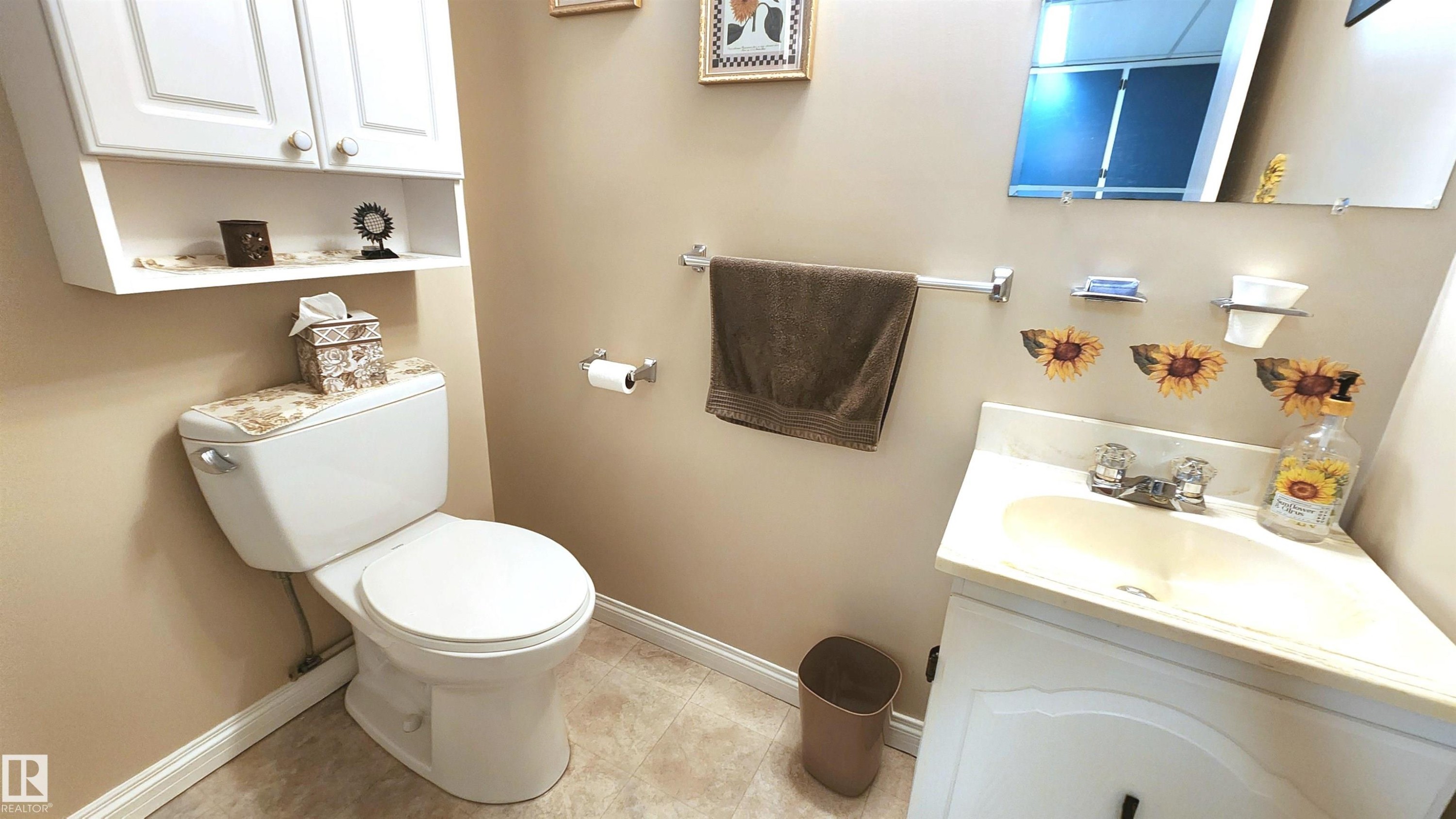 Bathroom featuring a vanity with an integrated sink, a wall-mounted mirror, and a toilet - 13307 Delwood Road, Edmonton, AB