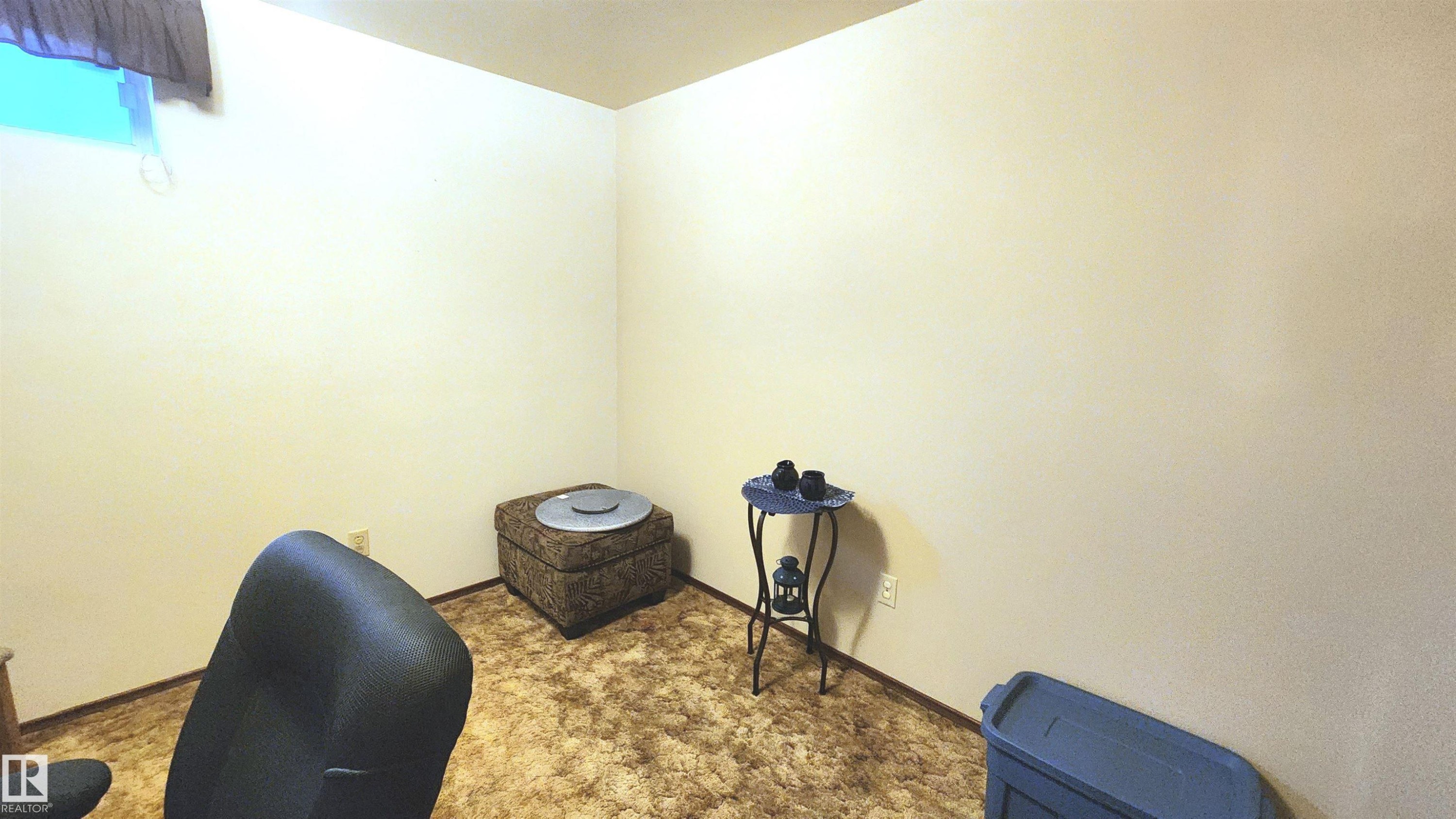 Carpeted room featuring light-toned walls and a corner window - 13307 Delwood Road, Edmonton, AB
