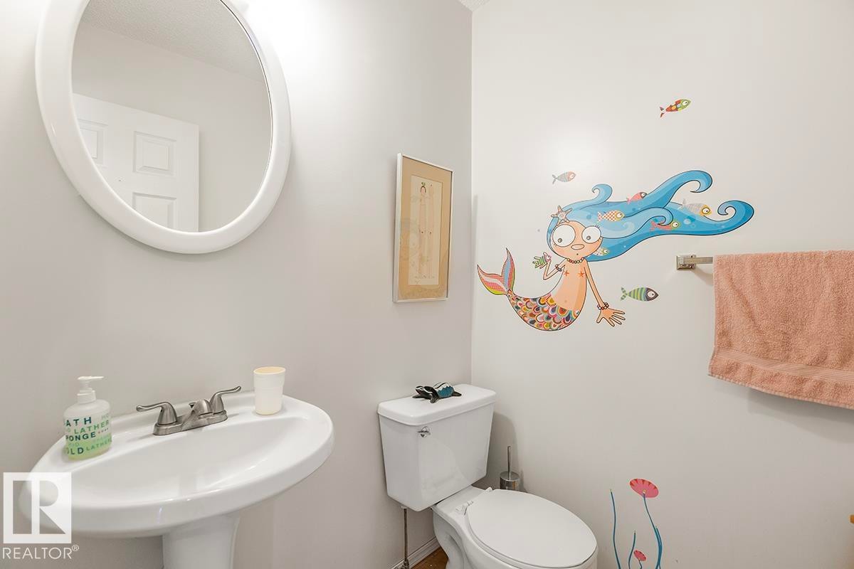 Bathroom featuring a pedestal sink, oval mirror, and toilet - 44 9630 176 Street, Edmonton, AB