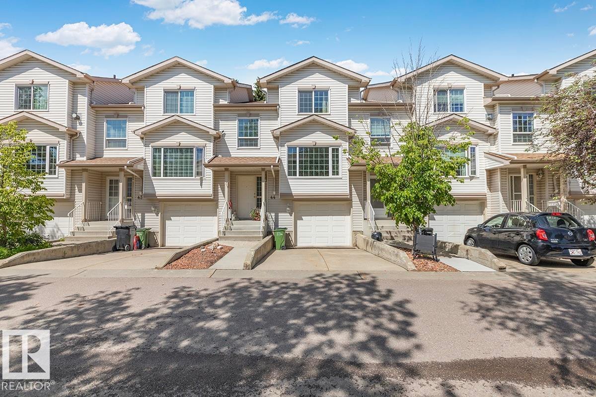 Townhouse exterior with light-colored siding, a covered front entry, and a single-car garage - 44 9630 176 Street, Edmonton, AB