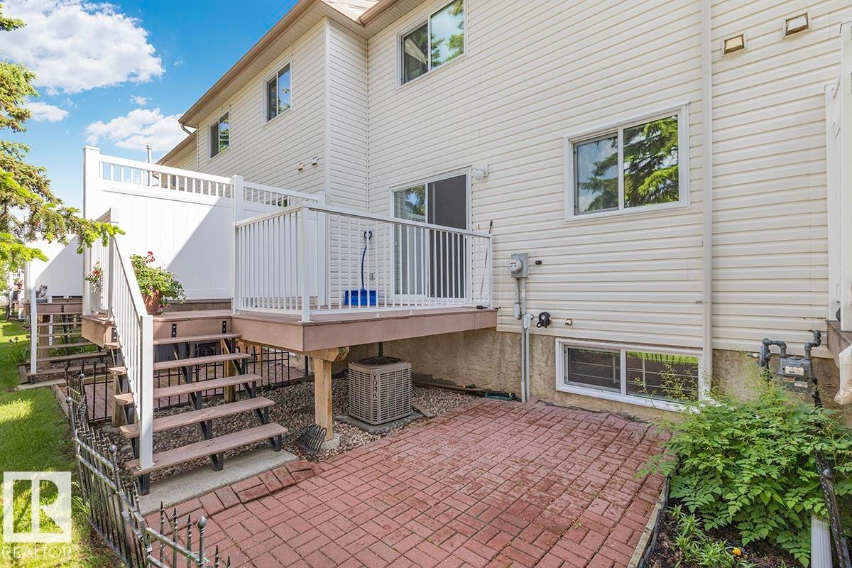 Rear exterior featuring a multi-level deck with white railings, a ground-level brick paver patio, and white vinyl siding - 44 9630 176 Street, Edmonton, AB