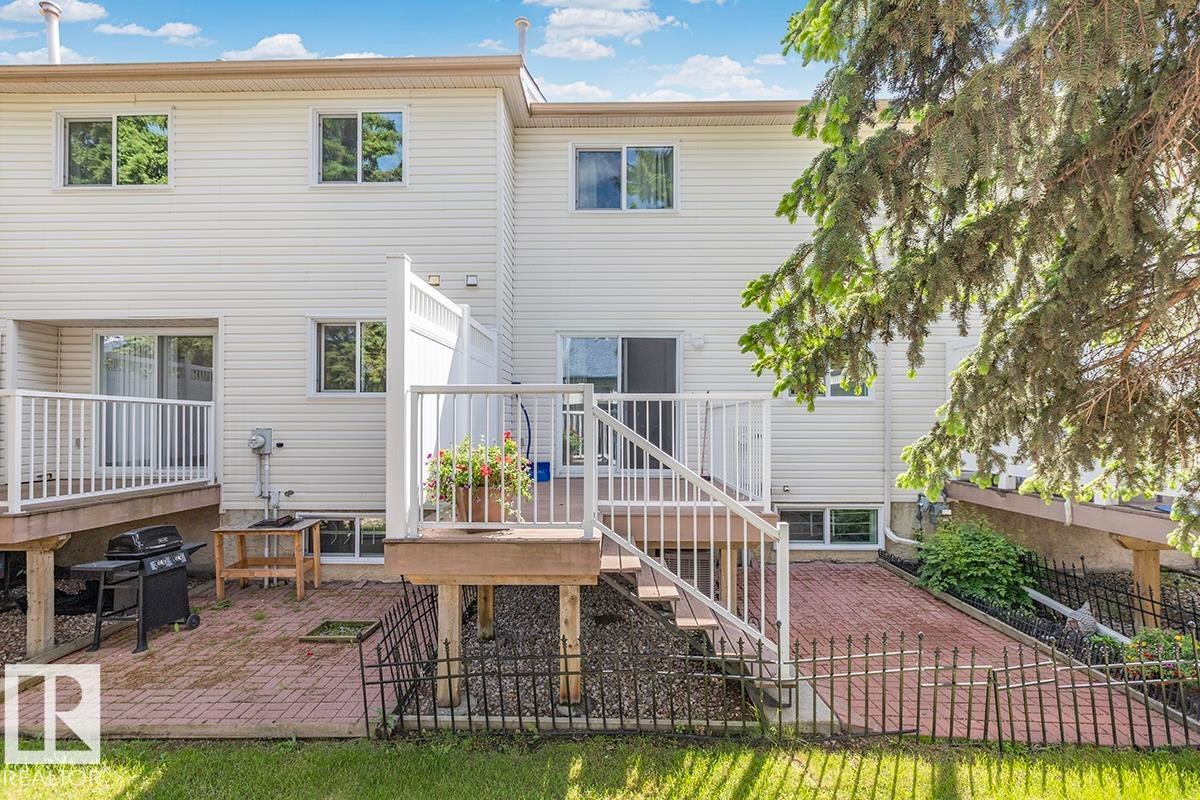 Rear exterior showcasing a white vinyl siding facade and two elevated wood decks with white railings - 44 9630 176 Street, Edmonton, AB