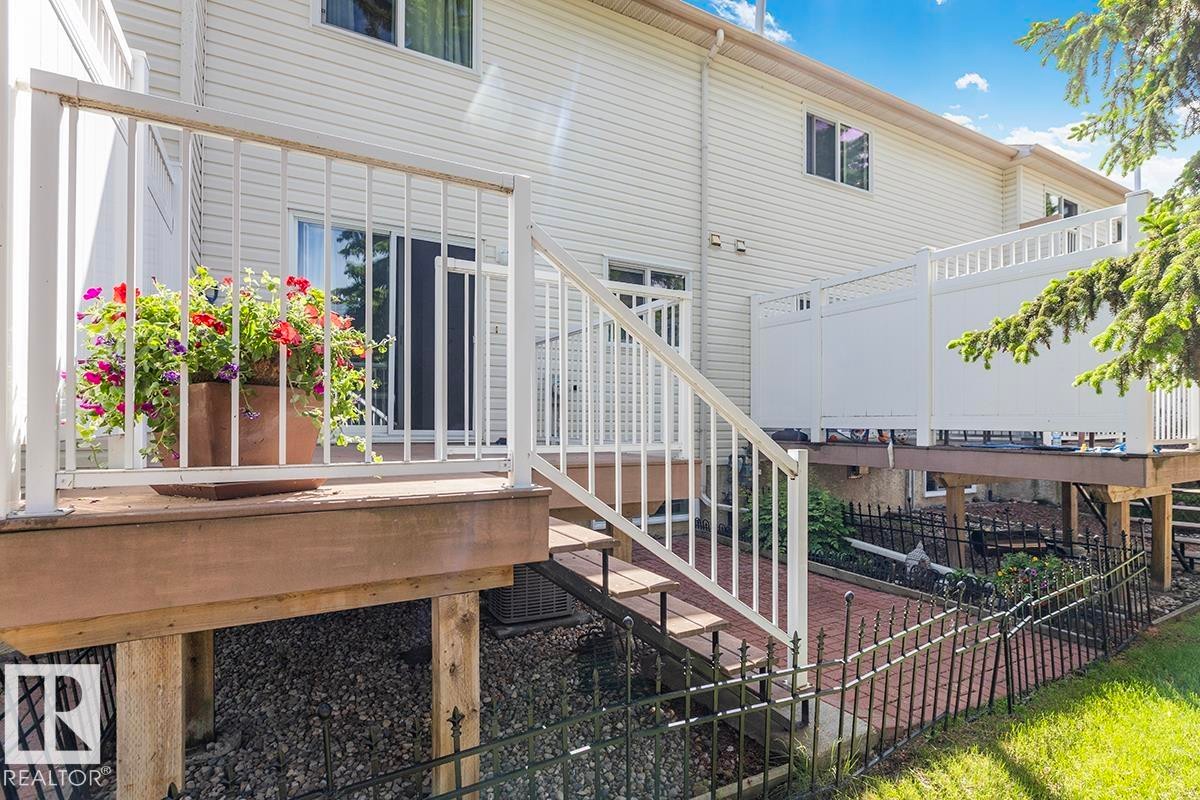 Multi-level deck with white railing, featuring exterior siding, sliding glass door, and staircase access - 44 9630 176 Street, Edmonton, AB