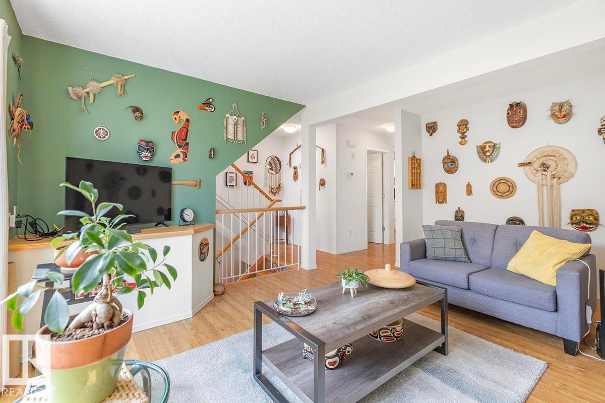 Bright living area featuring wood-finish flooring, a contemporary staircase with white balusters, and a built-in media console - 44 9630 176 Street, Edmonton, AB