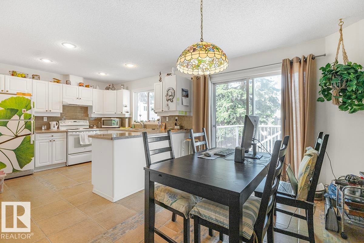 Open-concept kitchen and dining area featuring tile flooring, white cabinetry, and a central island with countertop space - 44 9630 176 Street, Edmonton, AB