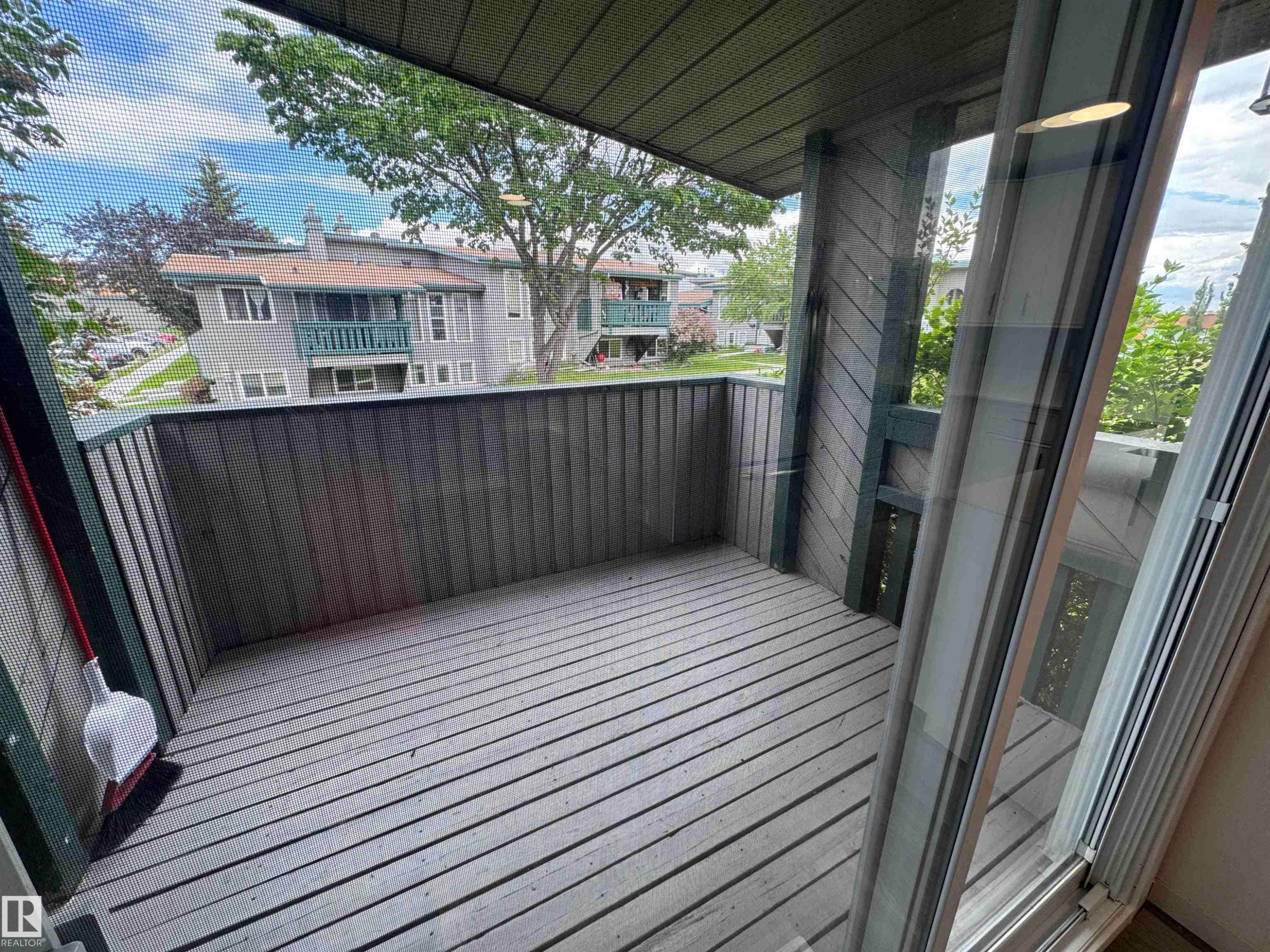 Private outdoor balcony featuring wood-finish decking and vertical wood paneling - 6441 180 Street, Edmonton, AB