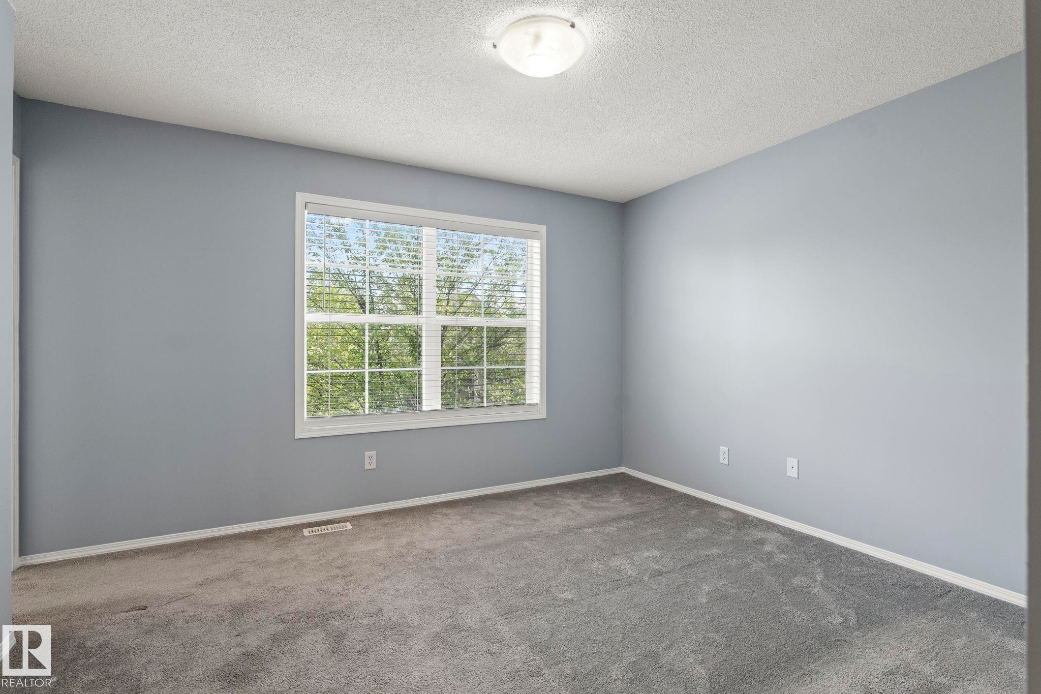 Spacious room featuring light blue walls, gray carpeting, and white trim - 7118 19A, Edmonton, AB - Indoor Photo Showing Other Room