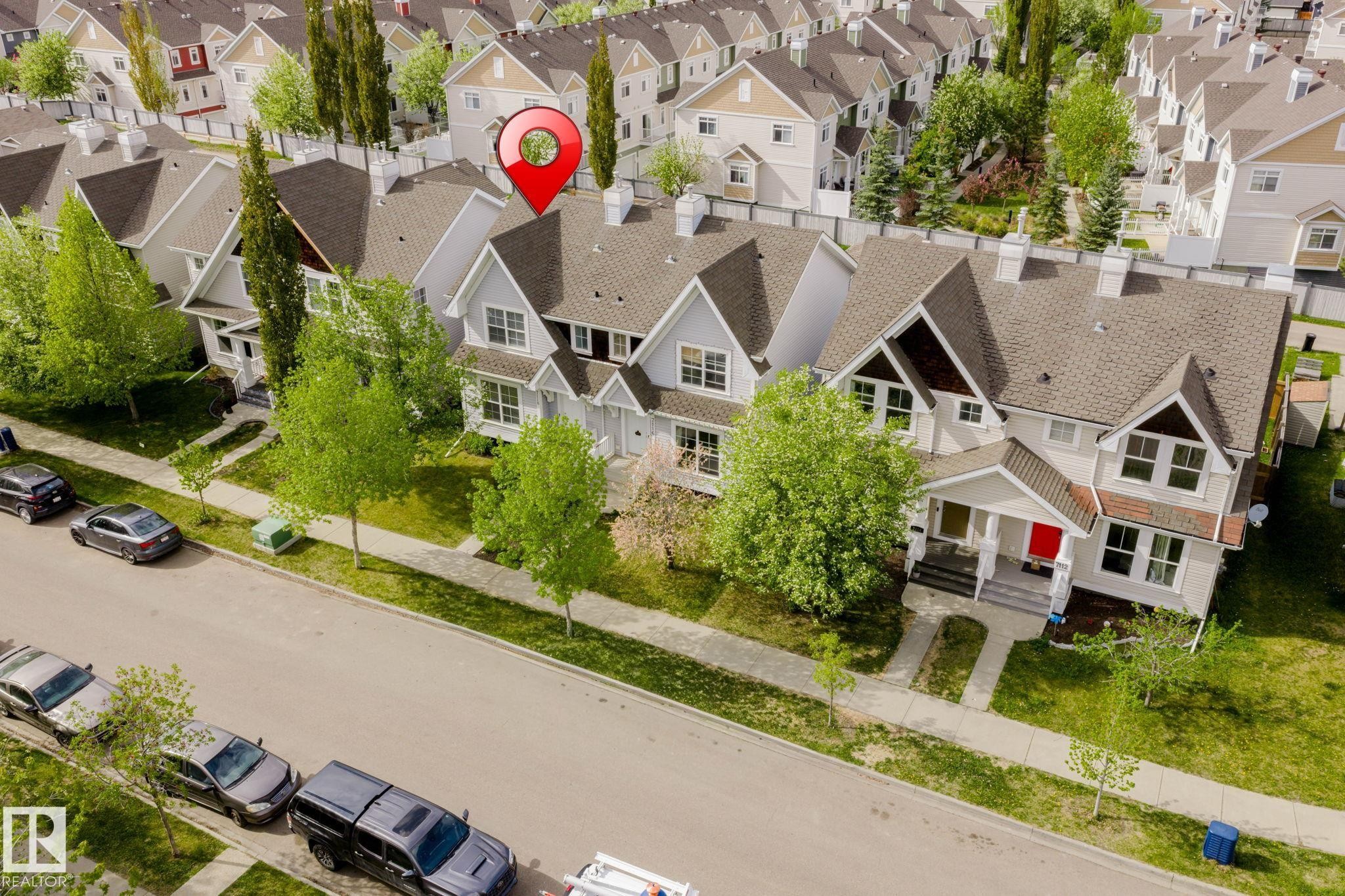 Exterior featuring a light-colored facade with dark brown gables, a prominent front porch with white columns, and multiple windows - 7118 19A, Edmonton, AB - Outdoor