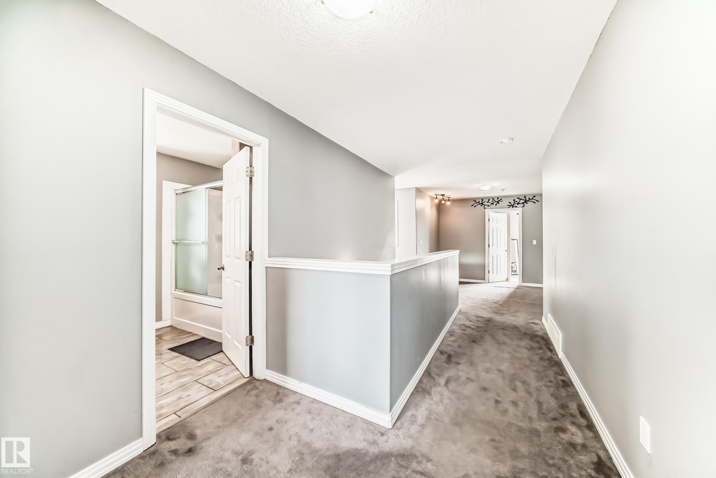 Hallway featuring light gray walls, white baseboards, and gray carpeting - 16720 61 Street Nw, Edmonton, AB - Indoor Photo Showing Other Room