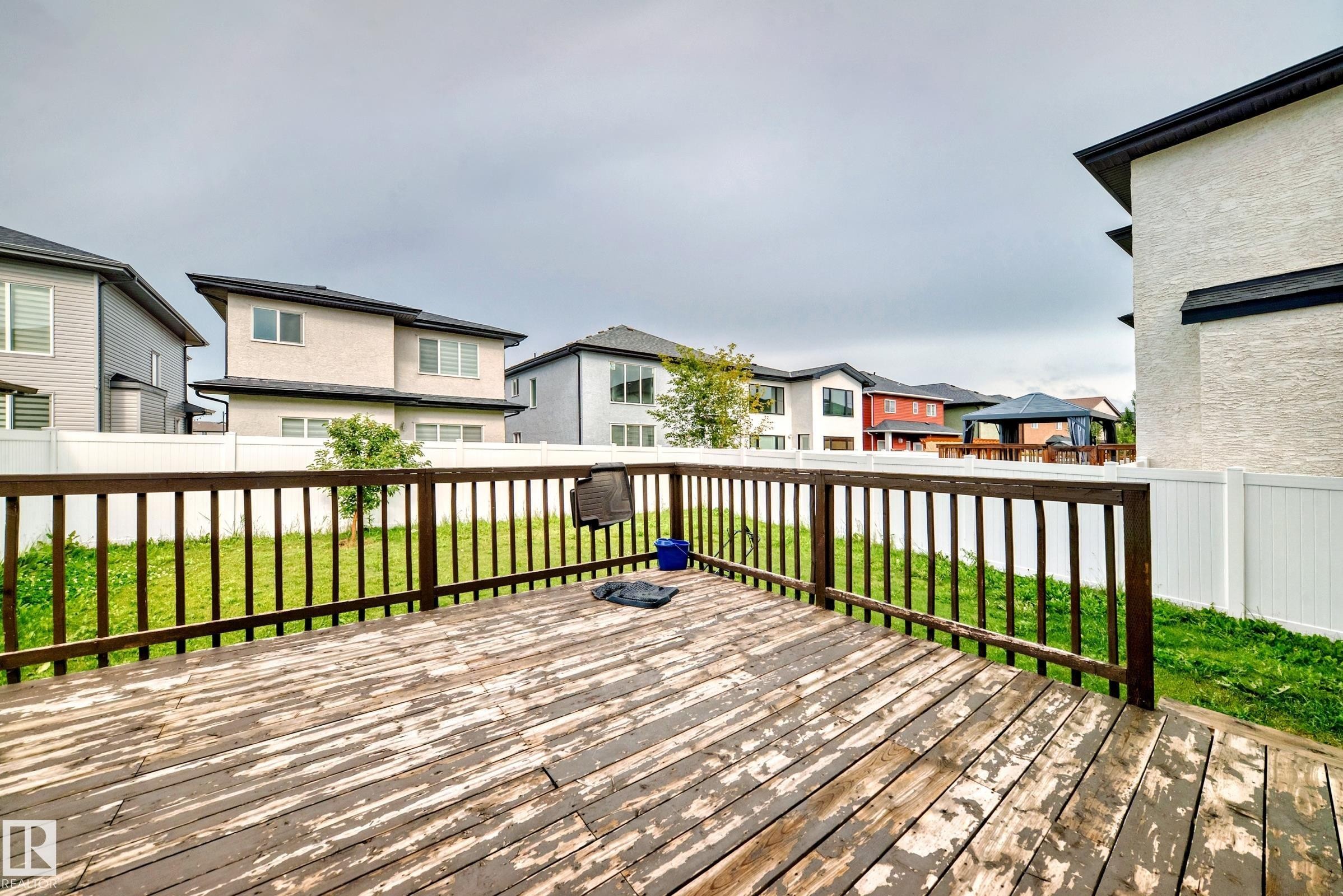 Spacious outdoor deck with a wooden railing system, featuring a grassy expanse and privacy fencing - 16720 61 Street Nw, Edmonton, AB - Outdoor With Deck Patio Veranda With Exterior