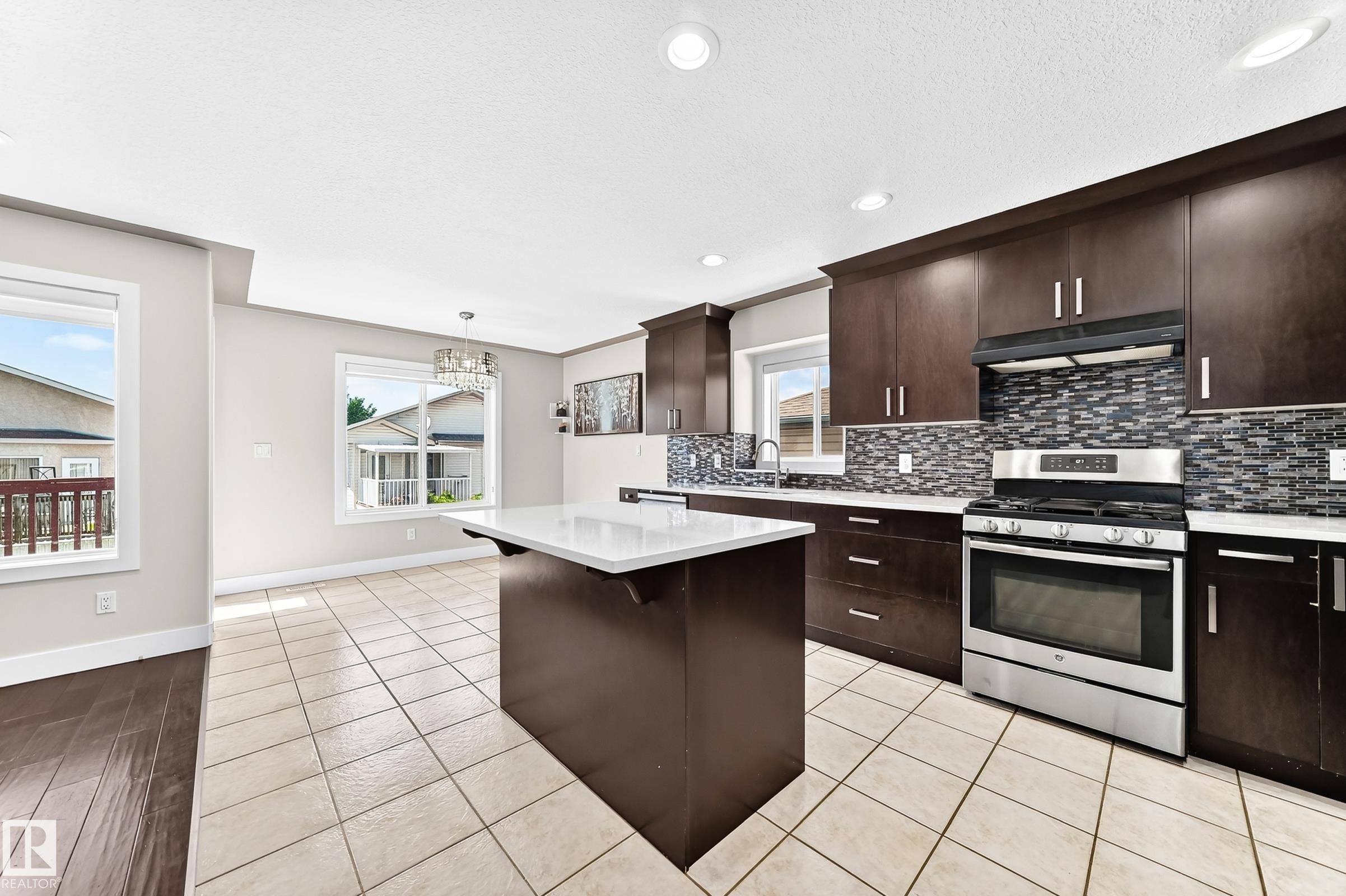 Modern kitchen featuring dark wood cabinetry, white countertops, and stainless steel appliances - 16124 76 Street, Edmonton, AB