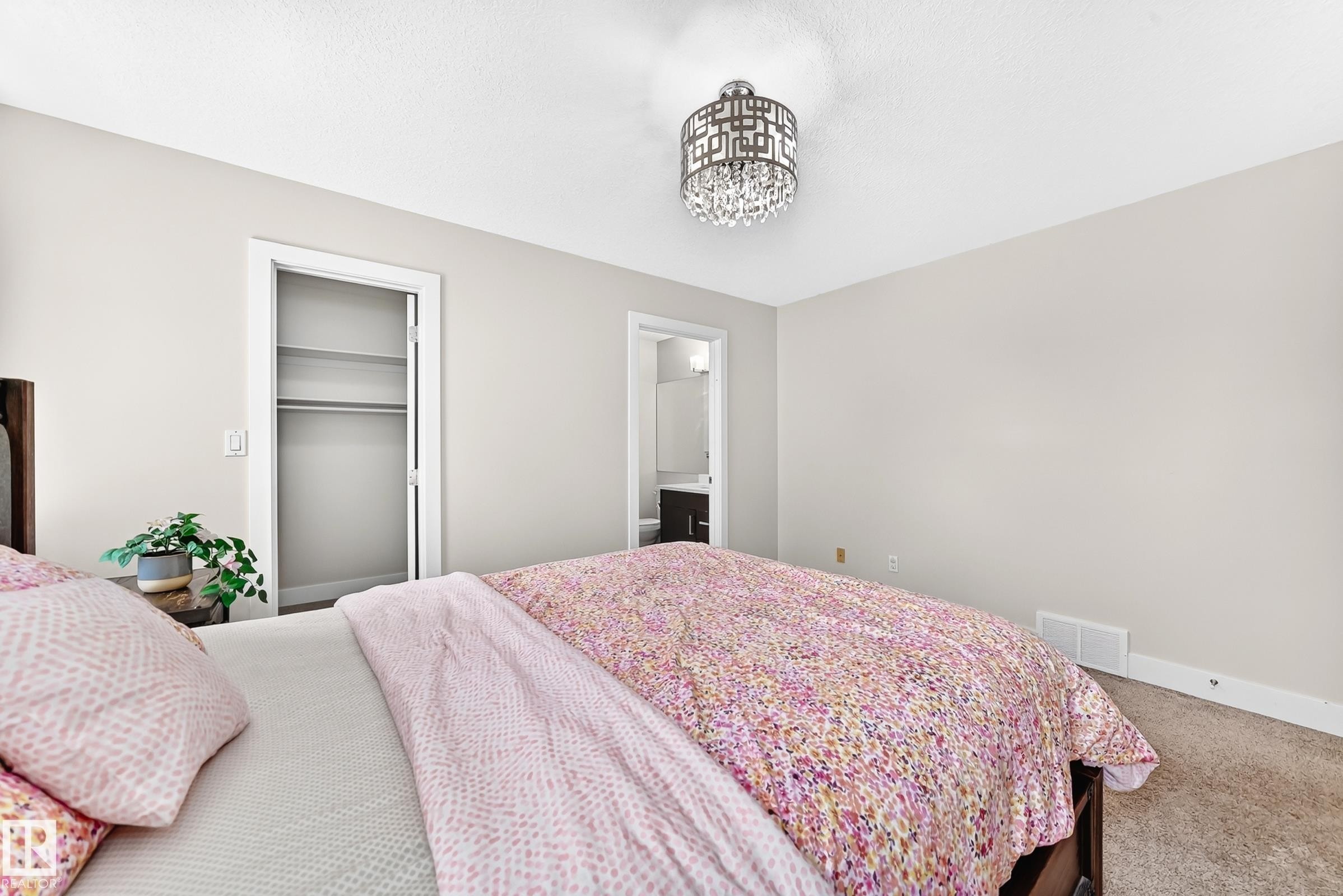 Plush carpeting, a built-in closet with shelving and hanging rod, and a contemporary chandelier fixture with crystal details - 16124 76 Street, Edmonton, AB