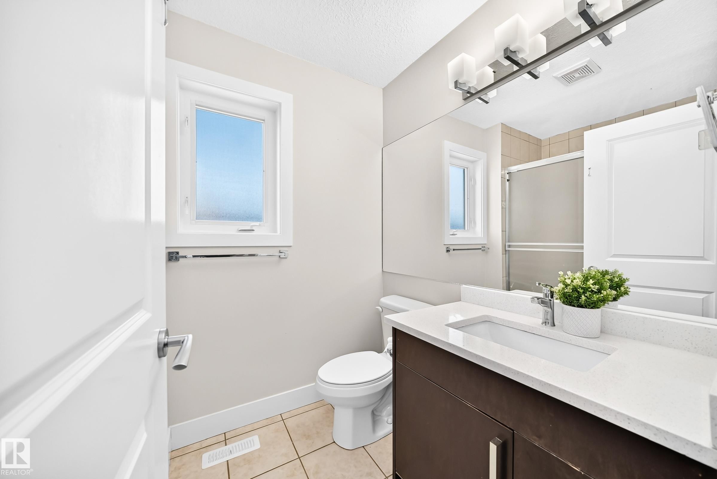 Bathroom featuring a dark wood-finish vanity with an integrated rectangular sink and a light-toned countertop - 16124 76 Street, Edmonton, AB
