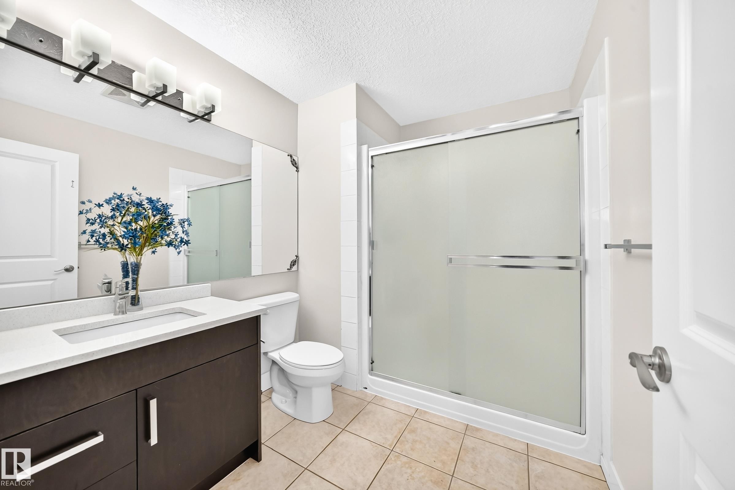 Bathroom featuring a dark wood-finish vanity with a white countertop and integrated sink - 16124 76 Street, Edmonton, AB