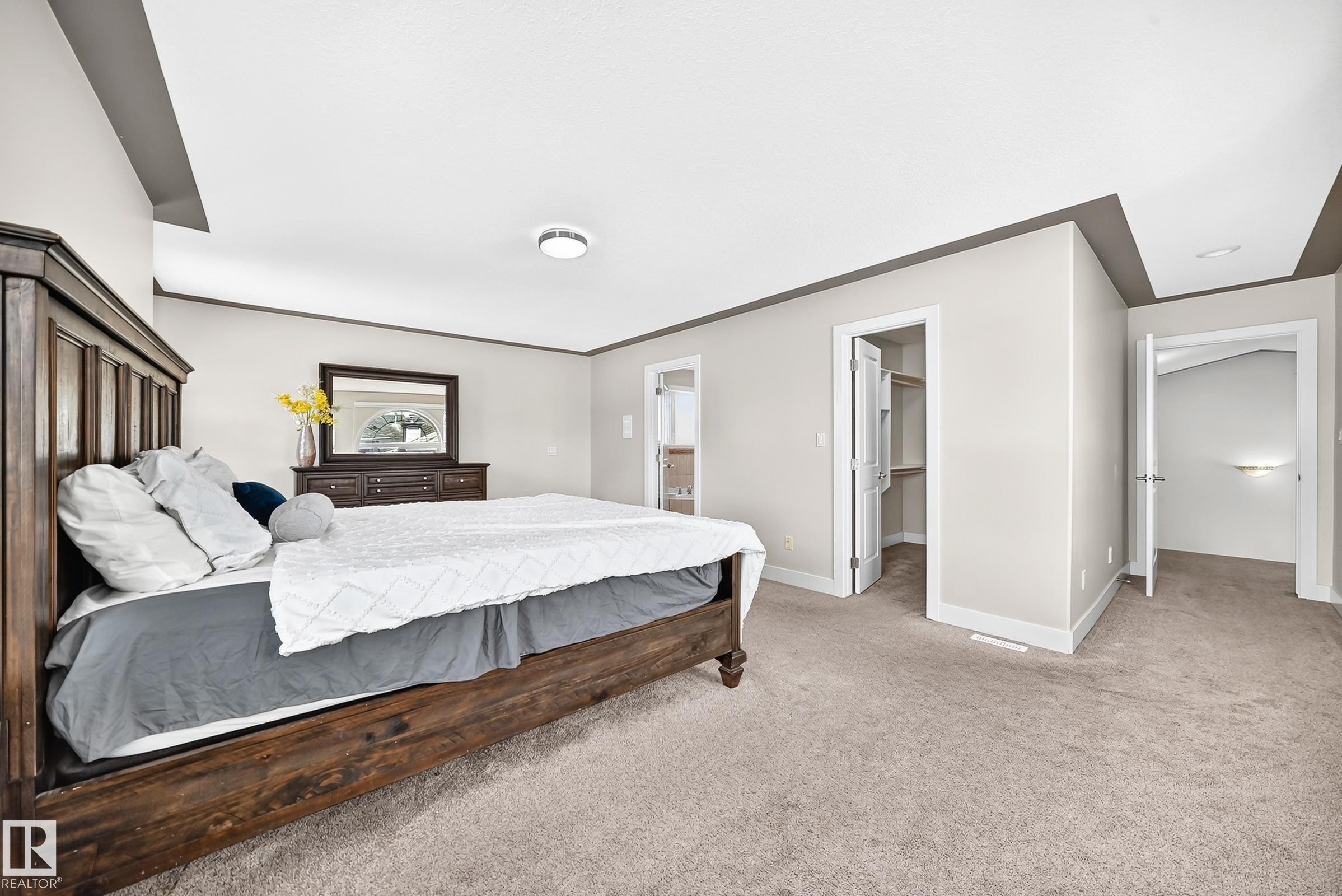 Spacious bedroom featuring light neutral wall tones, contrasting dark trim, and soft carpeting - 16124 76 Street, Edmonton, AB