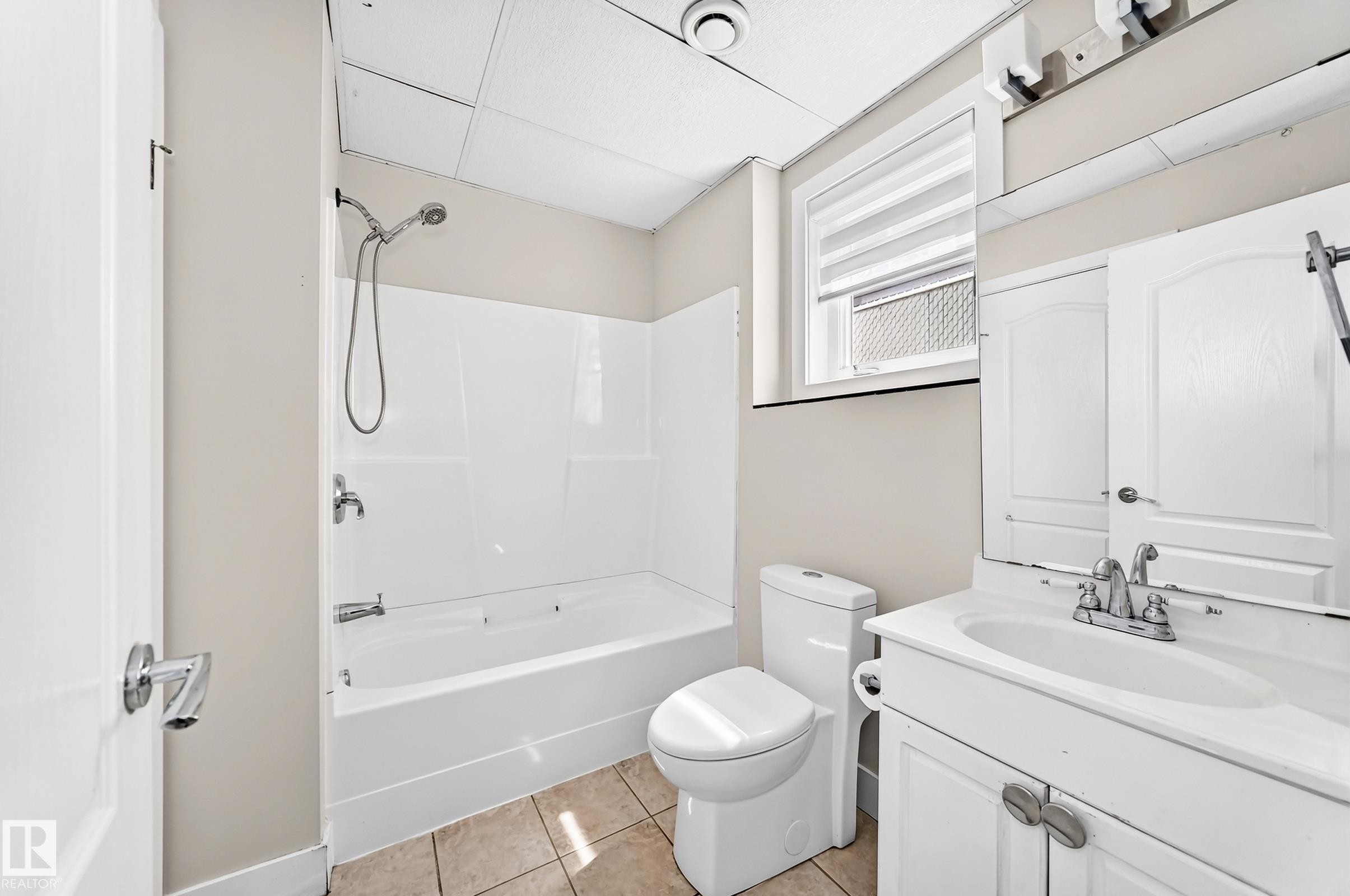 Bathroom featuring a white tub/shower combination, a white toilet, and a vanity with a sink and storage cabinetry - 16124 76 Street, Edmonton, AB