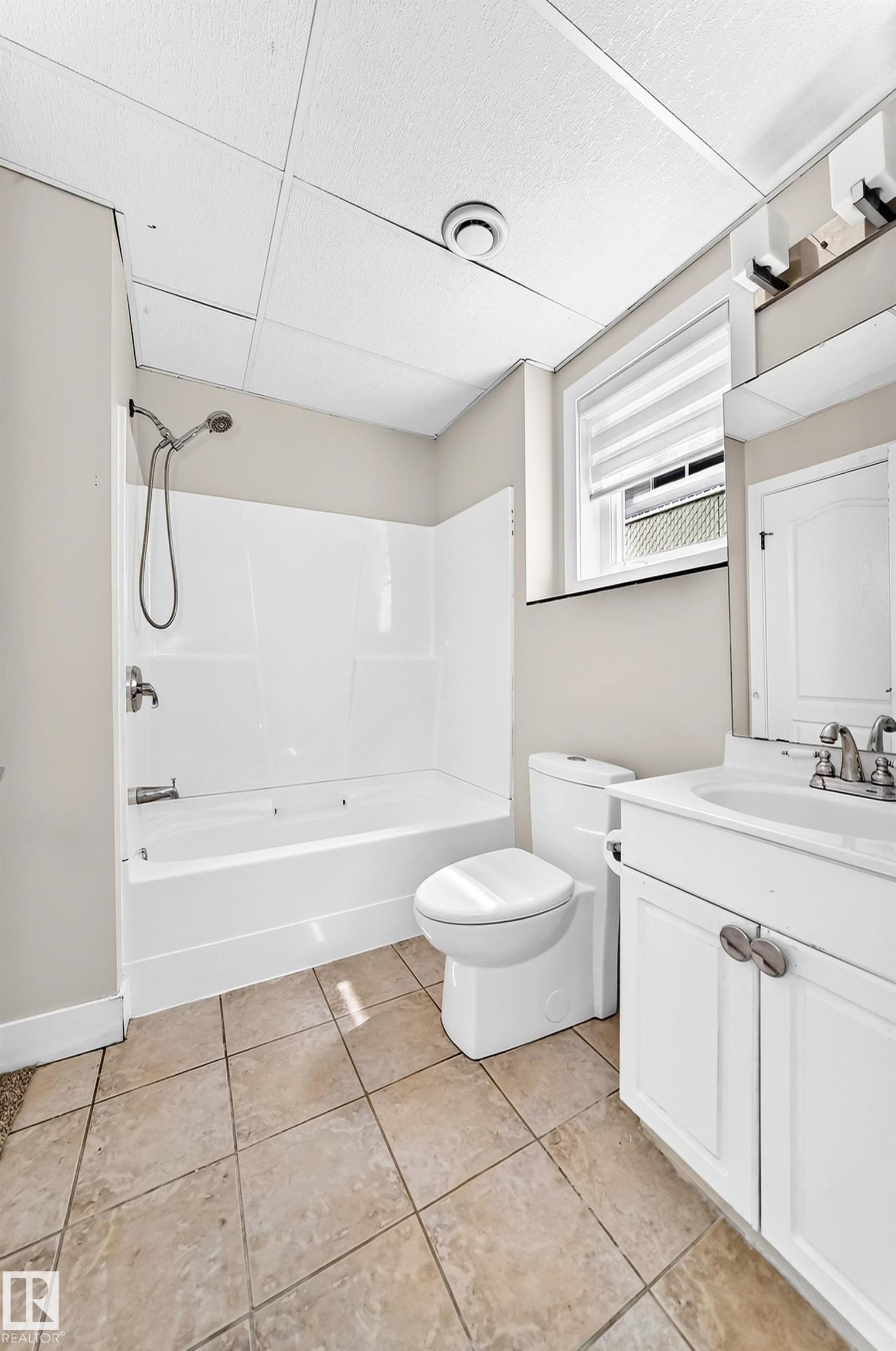 Bathroom featuring a white tub/shower combination, a white toilet, and a vanity with white cabinetry - 16124 76 Street, Edmonton, AB