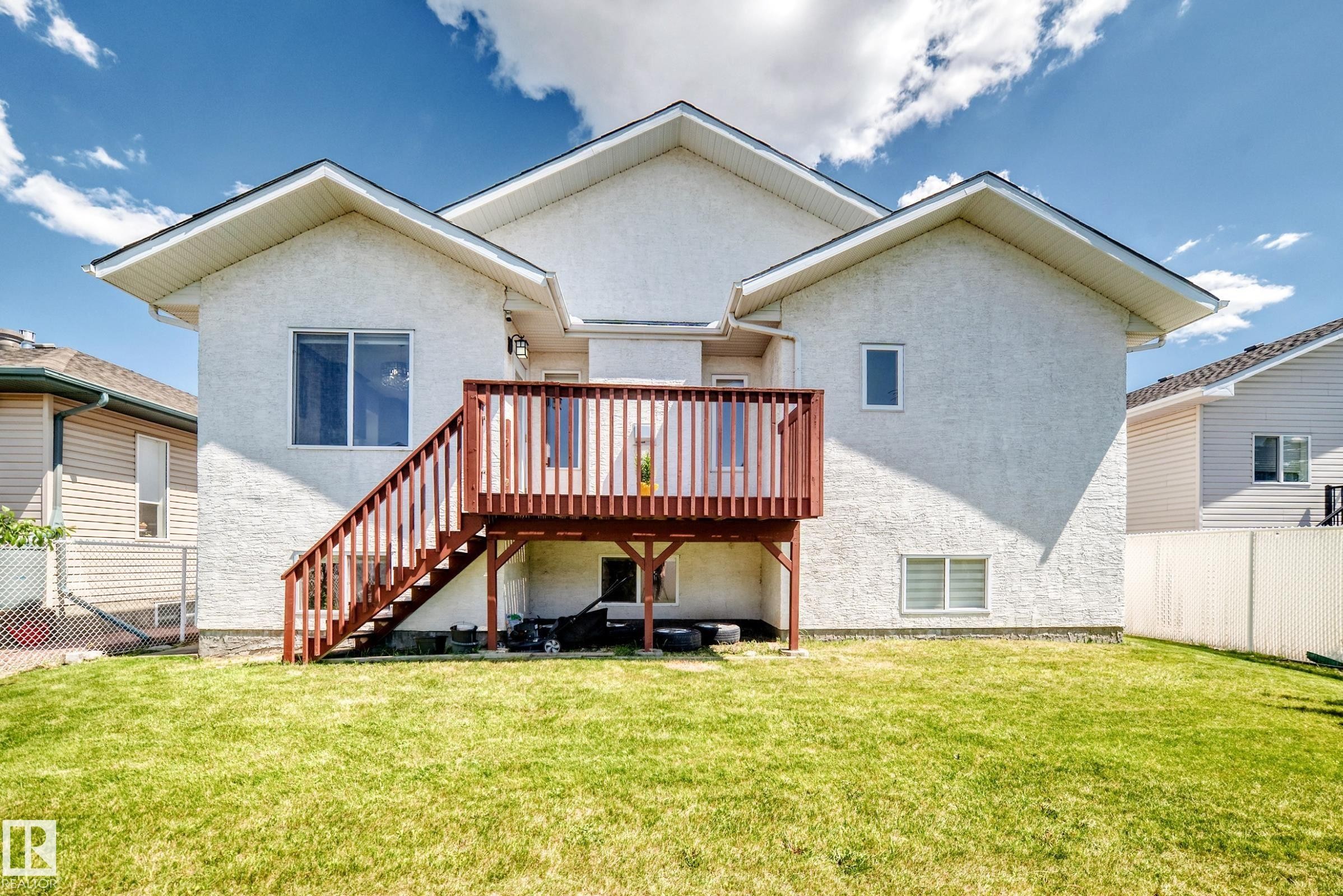 Rear exterior featuring a raised wooden deck with railings and stairs - 16124 76 Street, Edmonton, AB