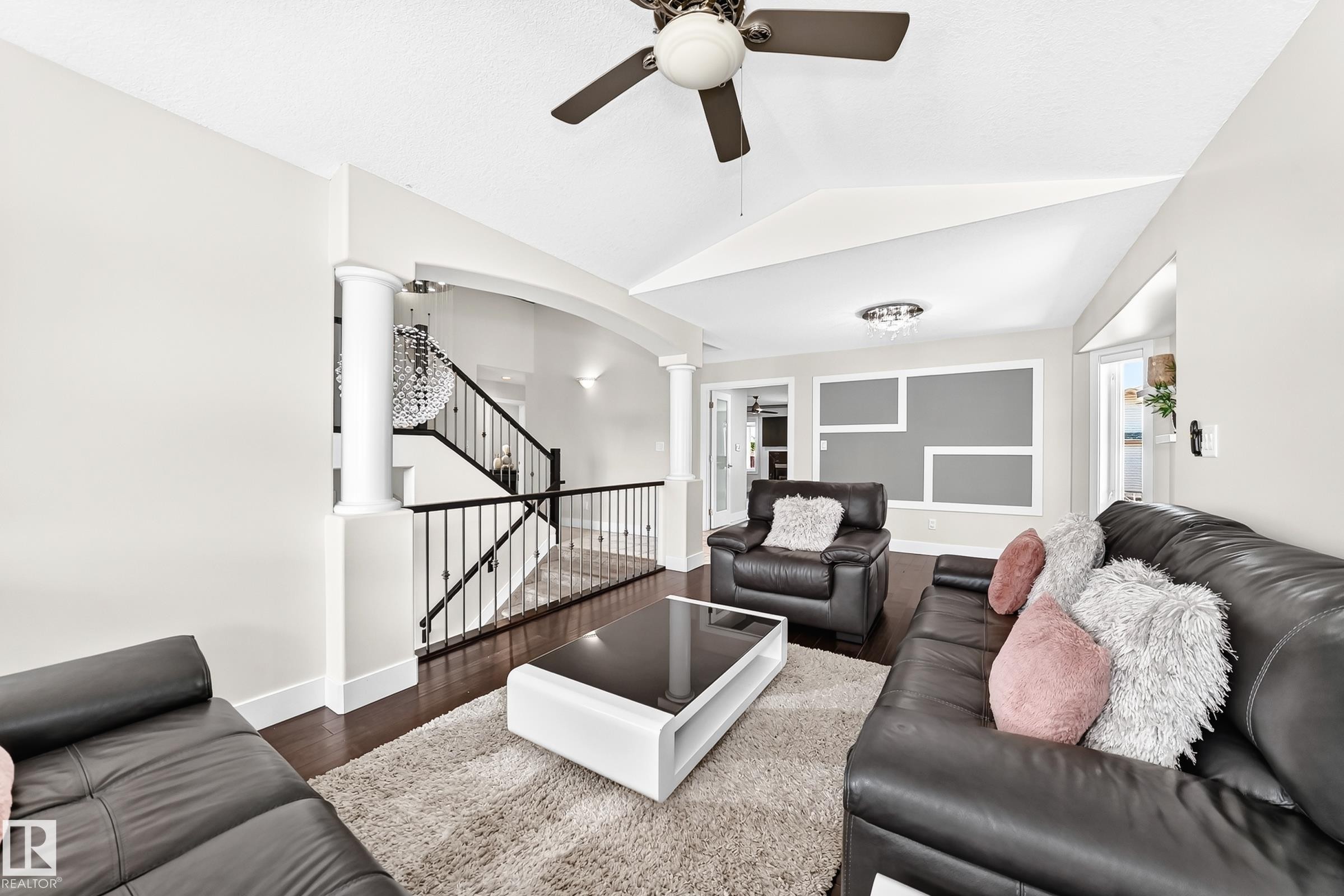 Living area featuring vaulted ceilings, a ceiling fan, dark wood-finish flooring, and white trim - 16124 76 Street, Edmonton, AB