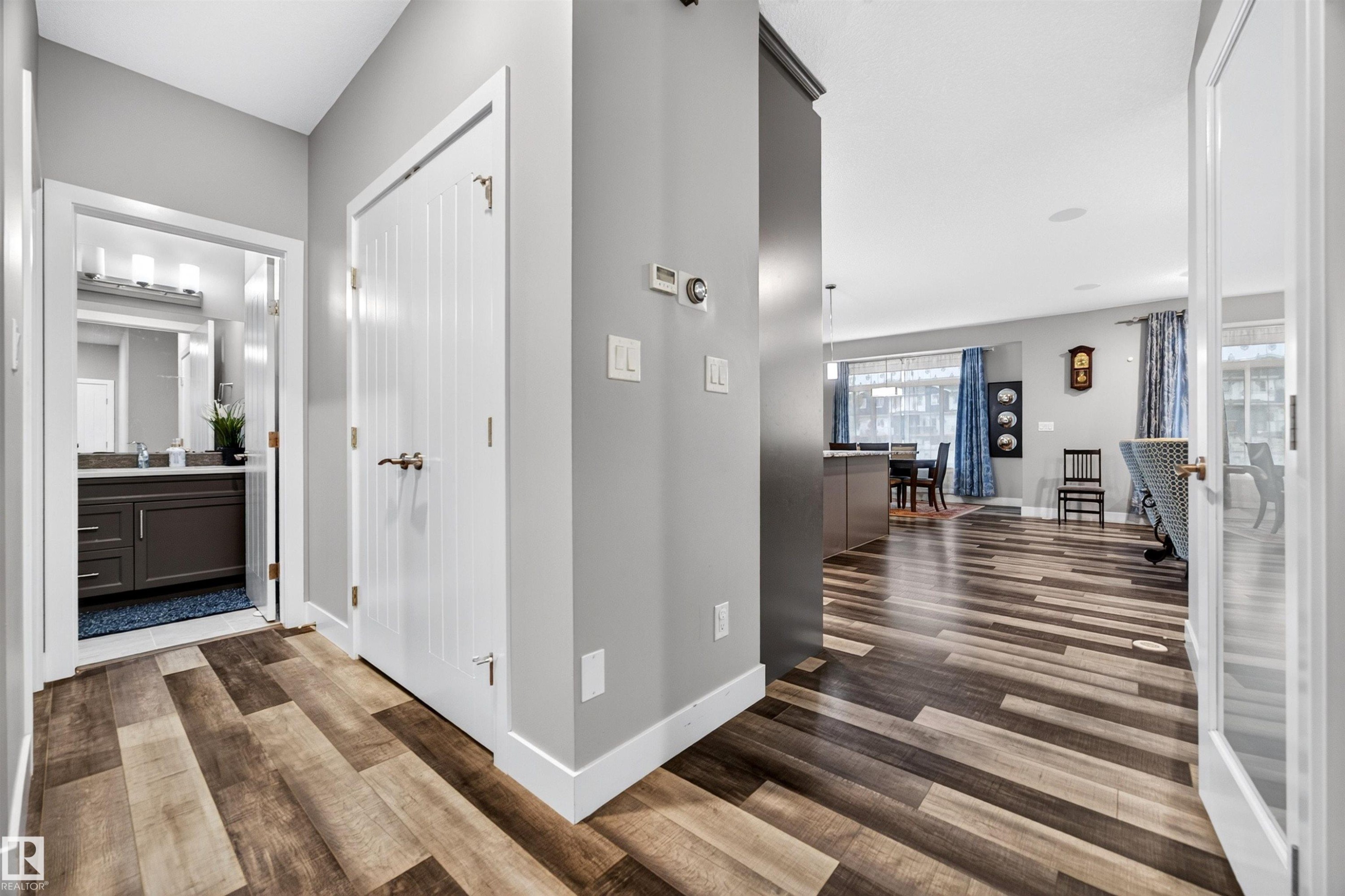 Hallway featuring wood-finish flooring, light gray walls, and white trim - 1603 158 Street, Edmonton, AB