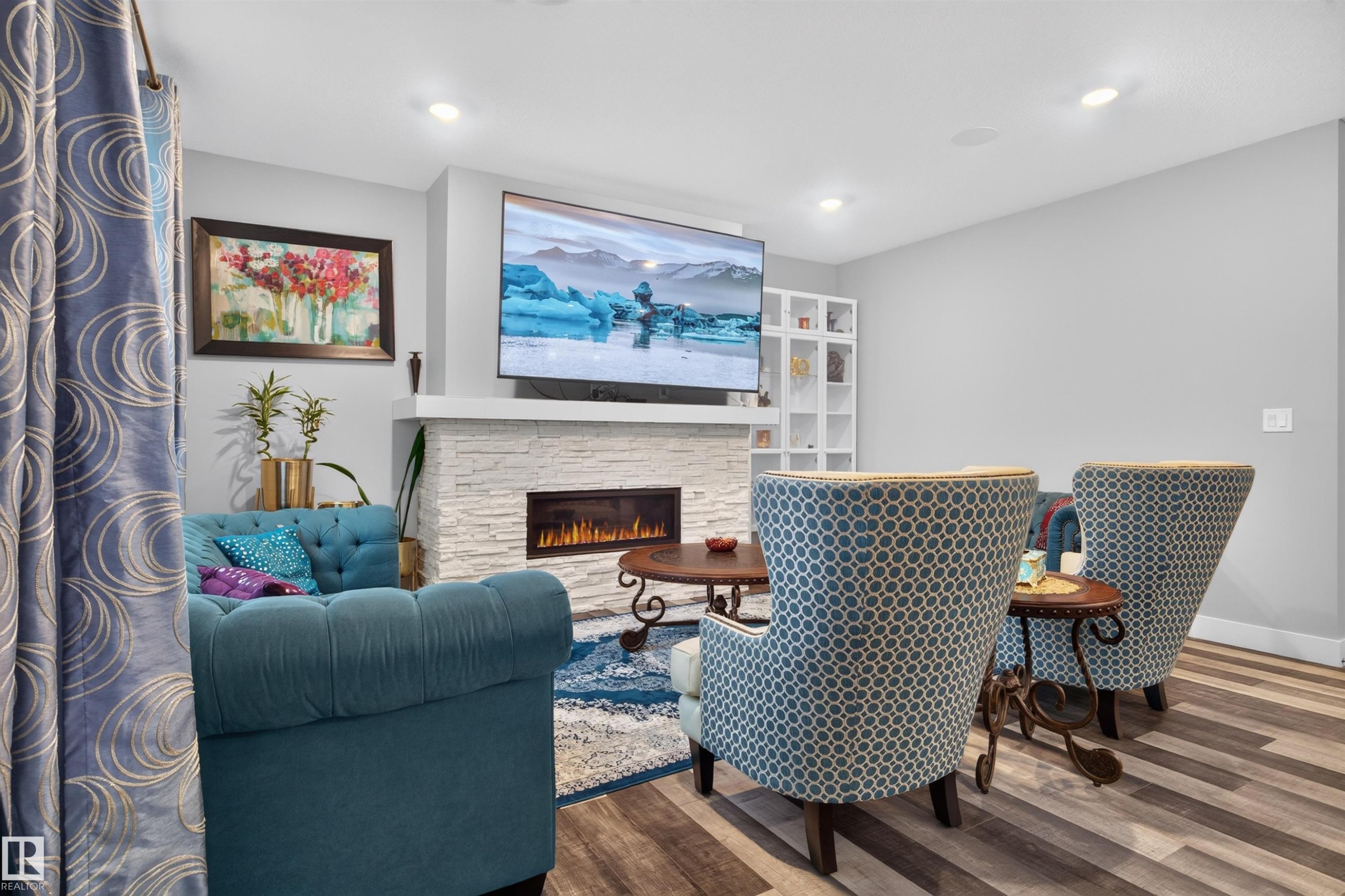 Living space featuring a stacked stone fireplace with an integrated linear electric insert, recessed lighting, and wood-finish flooring - 1603 158 Street, Edmonton, AB