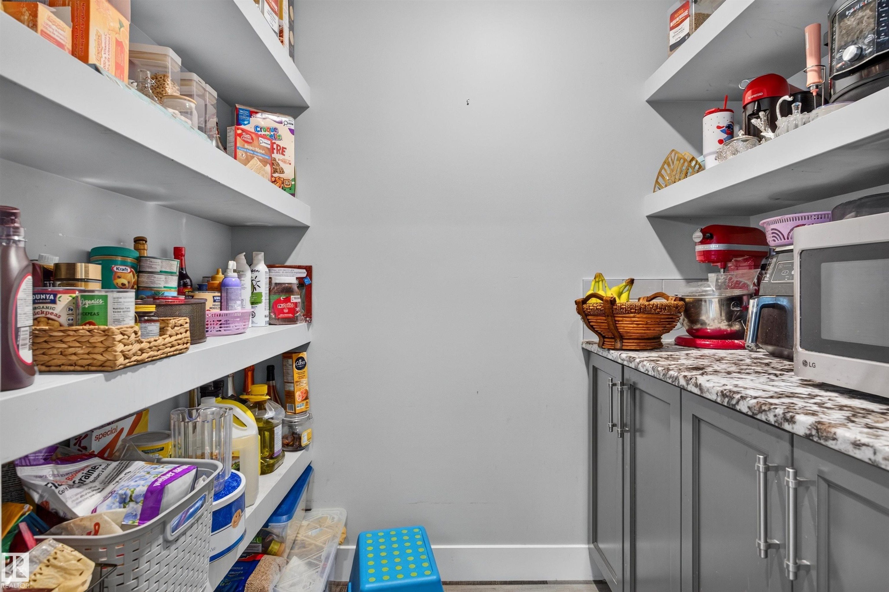 Custom pantry with extensive floating shelving, lower cabinetry, and a stone-finish countertop - 1603 158 Street, Edmonton, AB