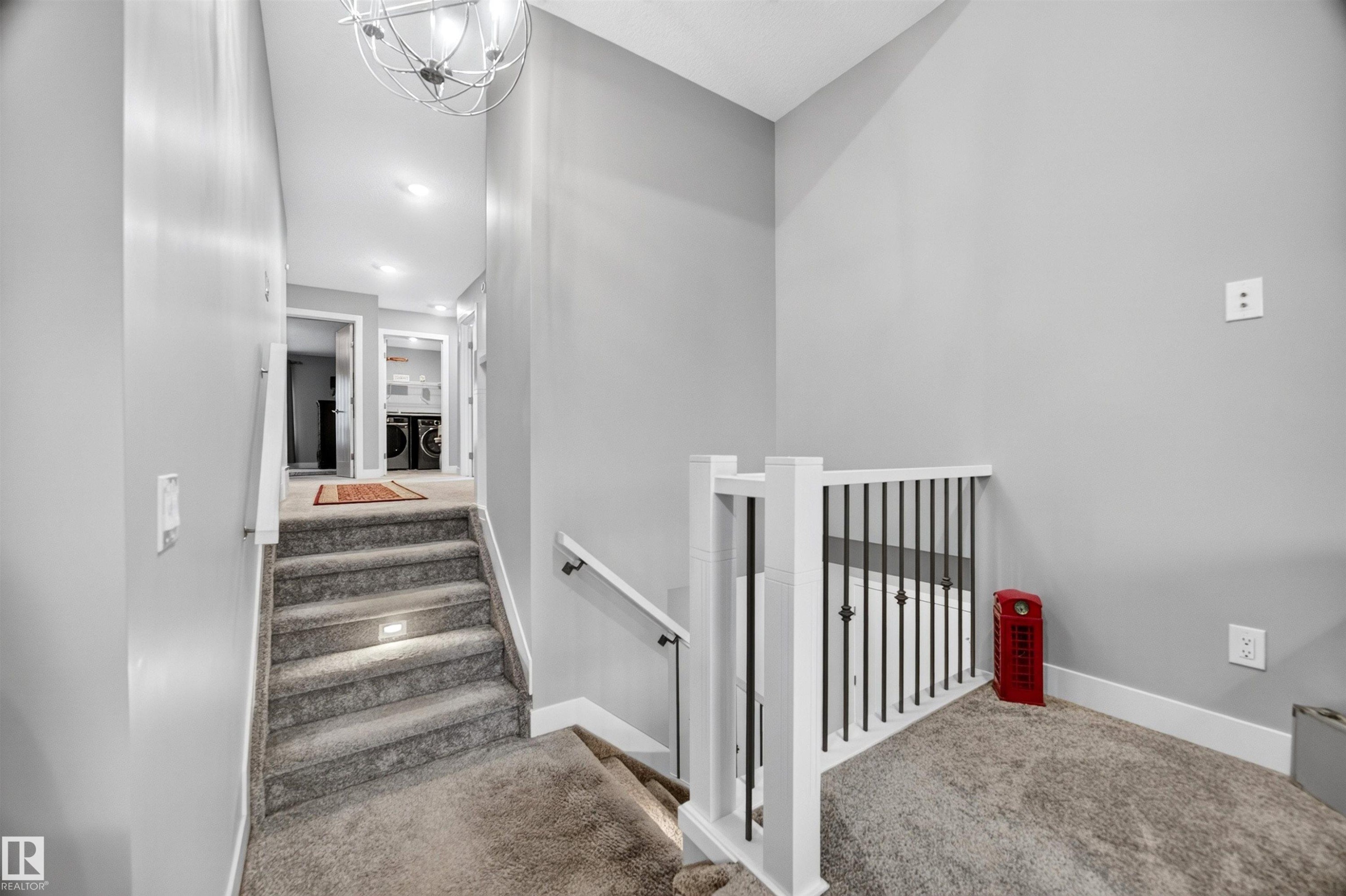 Carpeted staircase featuring inset step lighting and a white banister with black iron balusters - 1603 158 Street, Edmonton, AB