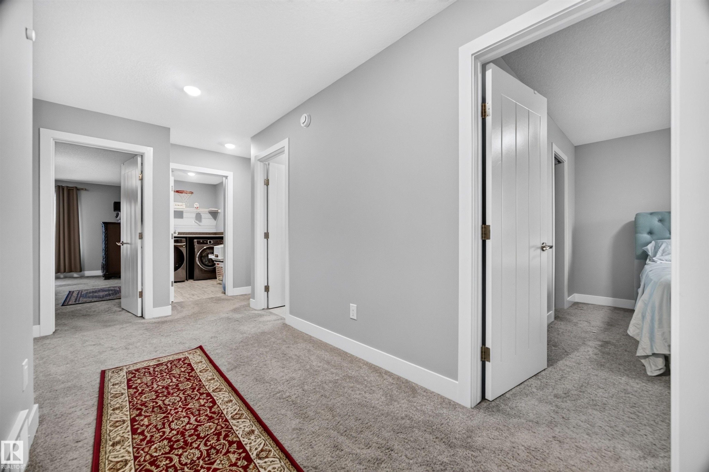 Central hallway featuring light gray walls, recessed lighting, and soft gray carpeting - 1603 158 Street, Edmonton, AB