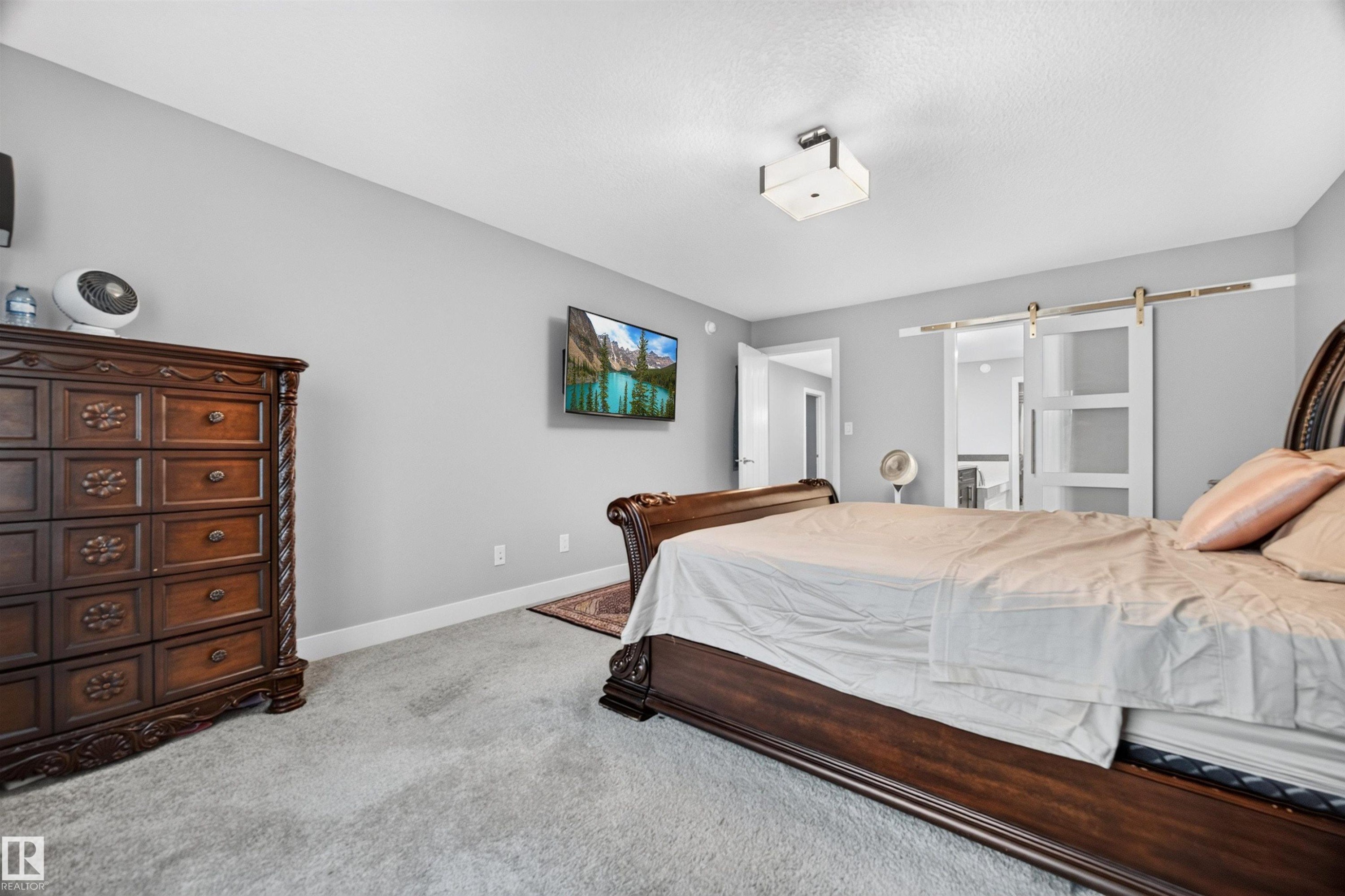 Bedroom featuring light gray wall paint, gray carpet flooring, a white trim baseboard, and a flush mount ceiling light - 1603 158 Street, Edmonton, AB