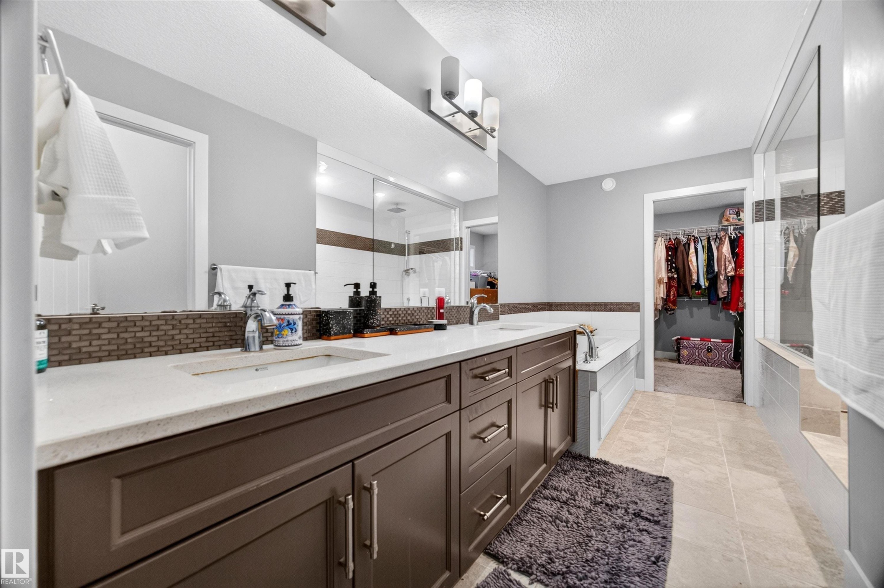 Contemporary bathroom featuring a long double vanity with integrated sinks, light-toned countertops, and dark cabinetry - 1603 158 Street, Edmonton, AB