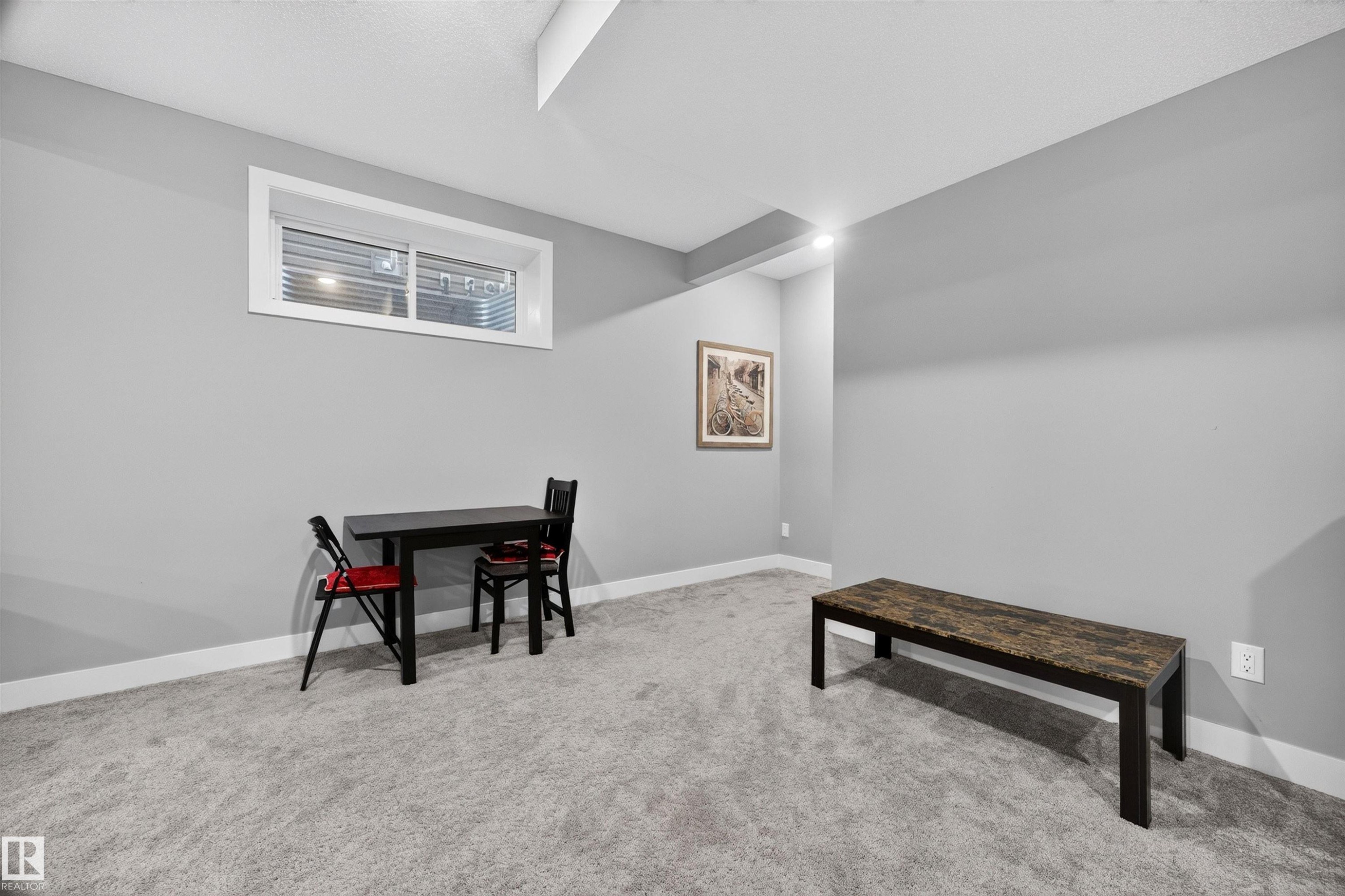 Spacious room featuring light gray wall paint, crisp white baseboards, and soft gray carpeting - 1603 158 Street, Edmonton, AB