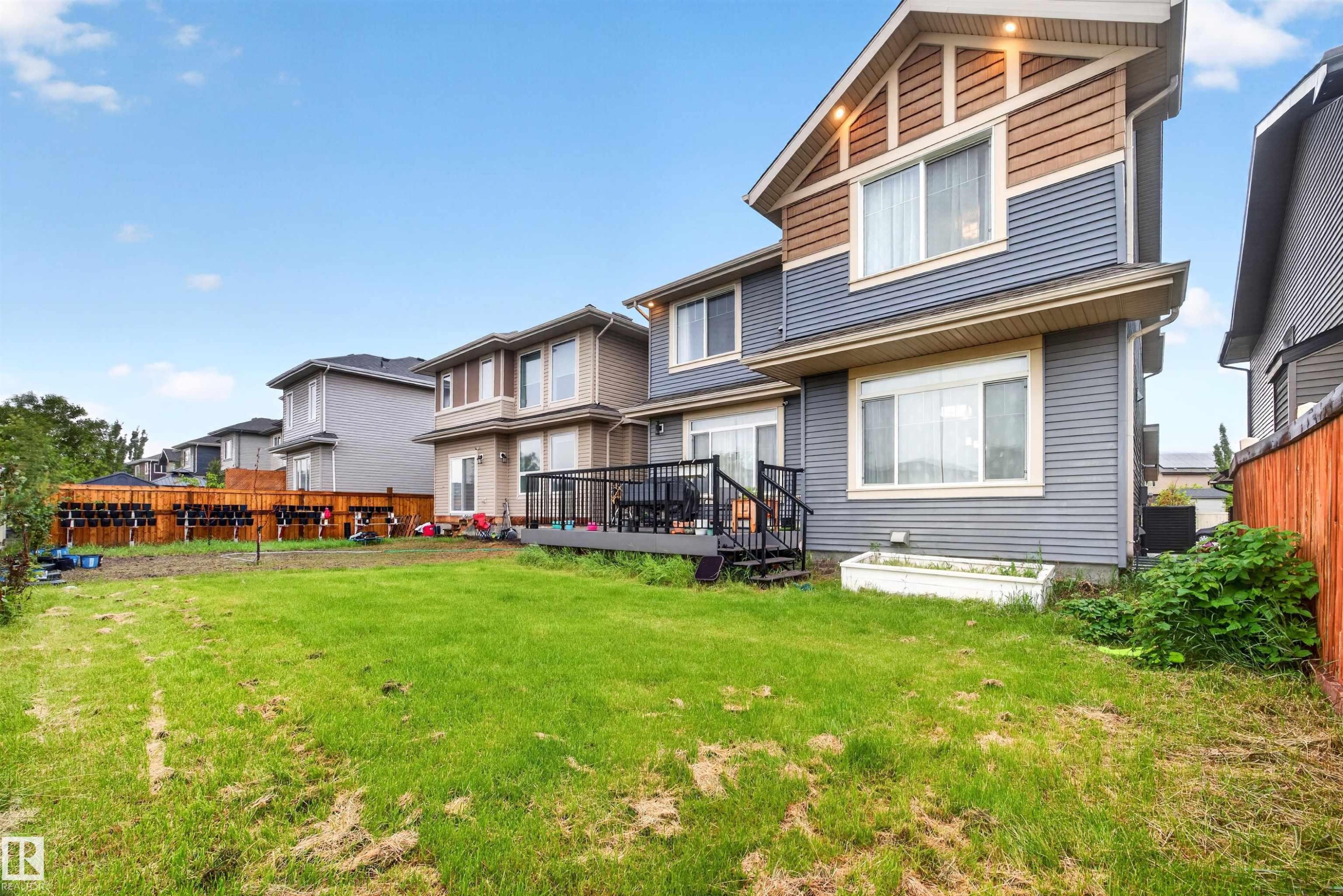 Rear exterior with multi-level siding and trim, featuring a ground-level patio door and an upper-level window - 1603 158 Street, Edmonton, AB