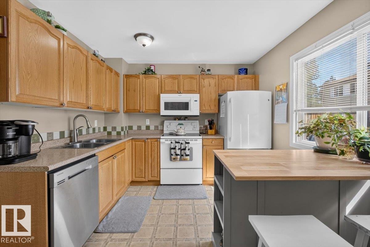 Kitchen featuring oak cabinetry and a built-in stainless steel dishwasher - 27 Walden Park, St. Albert, AB