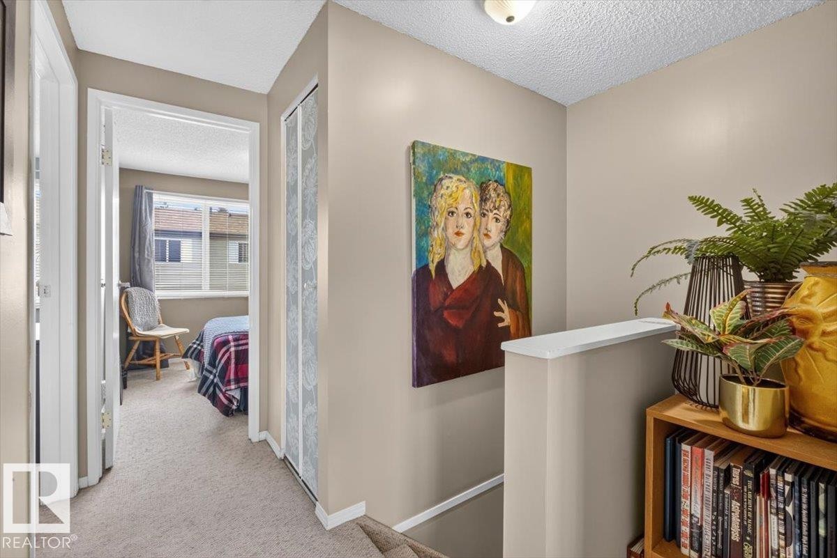 Carpeted hallway featuring neutral wall paint, white trim, and a ceiling-mounted light fixture - 27 Walden Park, St. Albert, AB