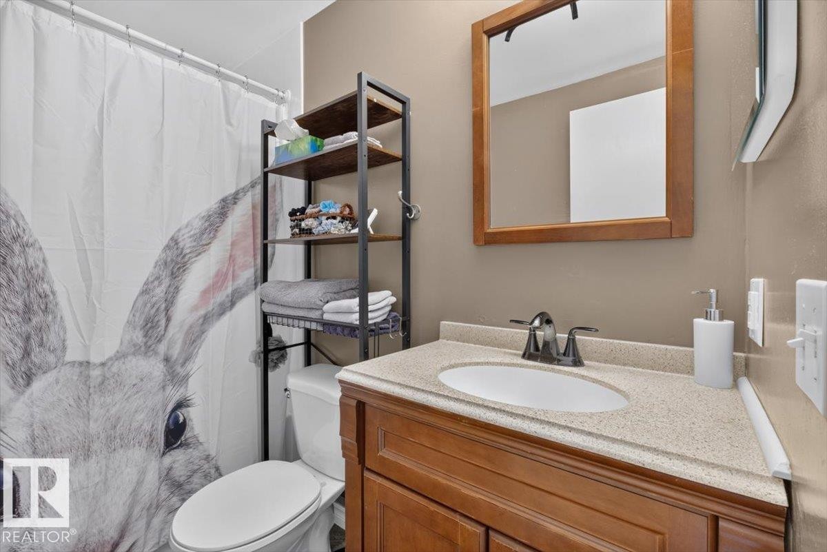 Bathroom featuring a wood vanity with an integrated sink, a light-colored countertop, and a wood-framed mirror - 27 Walden Park, St. Albert, AB