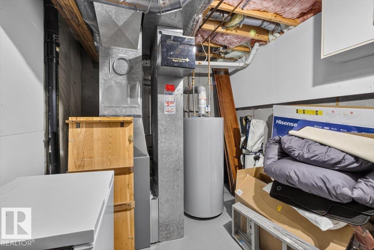 Utility area featuring a water heater, furnace, and exposed ceiling joists with insulation - 27 Walden Park, St. Albert, AB