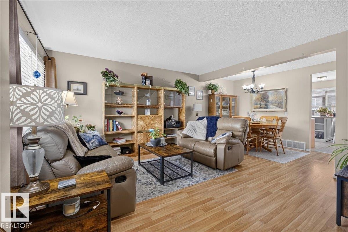 Bright interior featuring wood-finish flooring, neutral wall tones, and a dining area - 27 Walden Park, St. Albert, AB