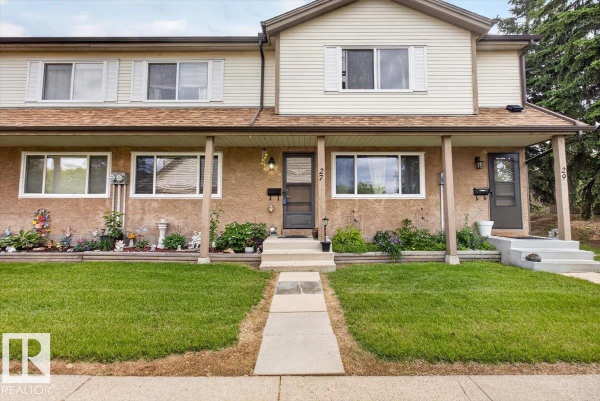 Front exterior featuring a covered porch, light-colored siding, and a gabled roofline - 27 Walden Park, St. Albert, AB