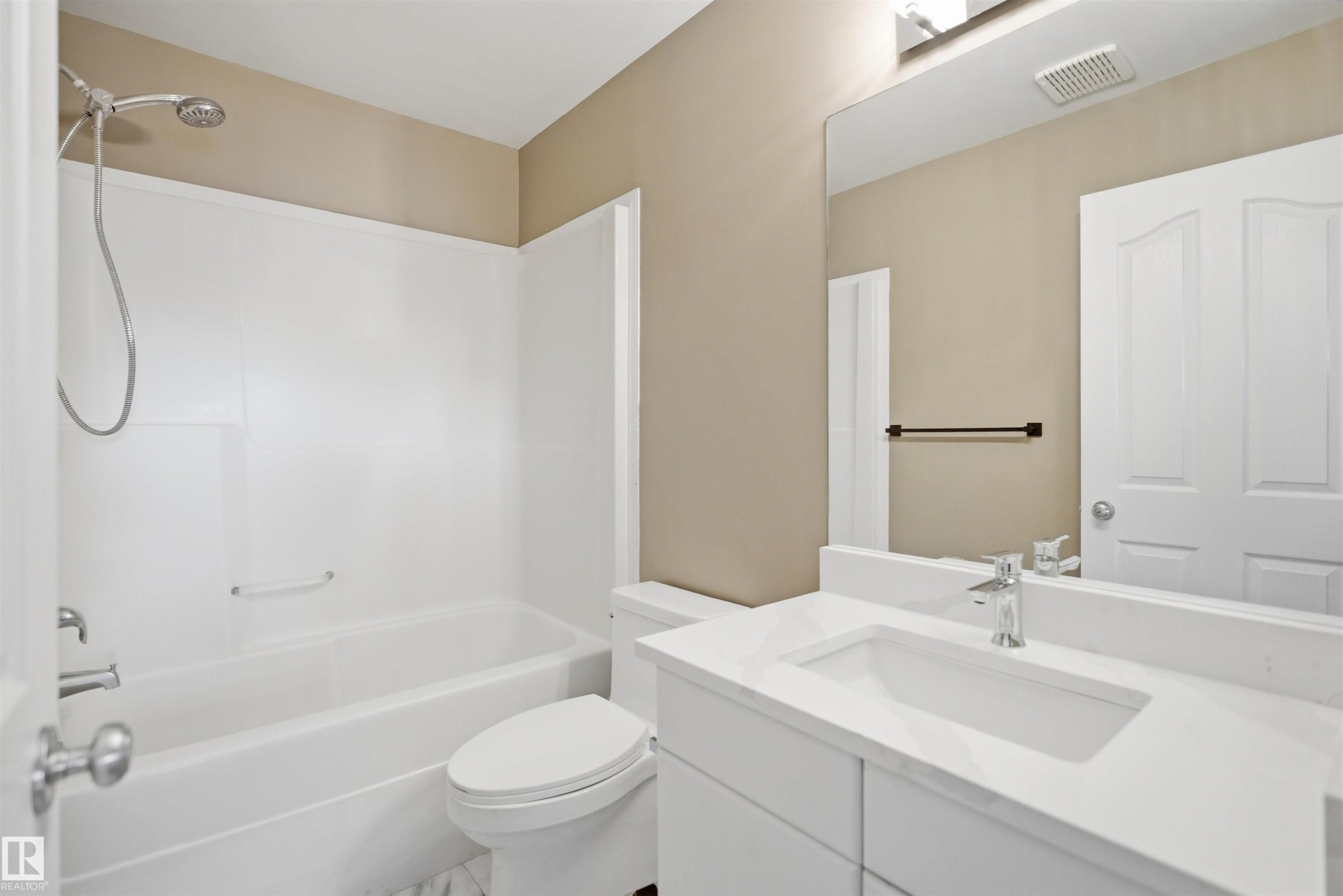 Bathroom featuring a white vanity with an integrated sink, polished chrome faucet, and a large mirror - 2610 33A Street, Edmonton, AB - Indoor Photo Showing Bathroom