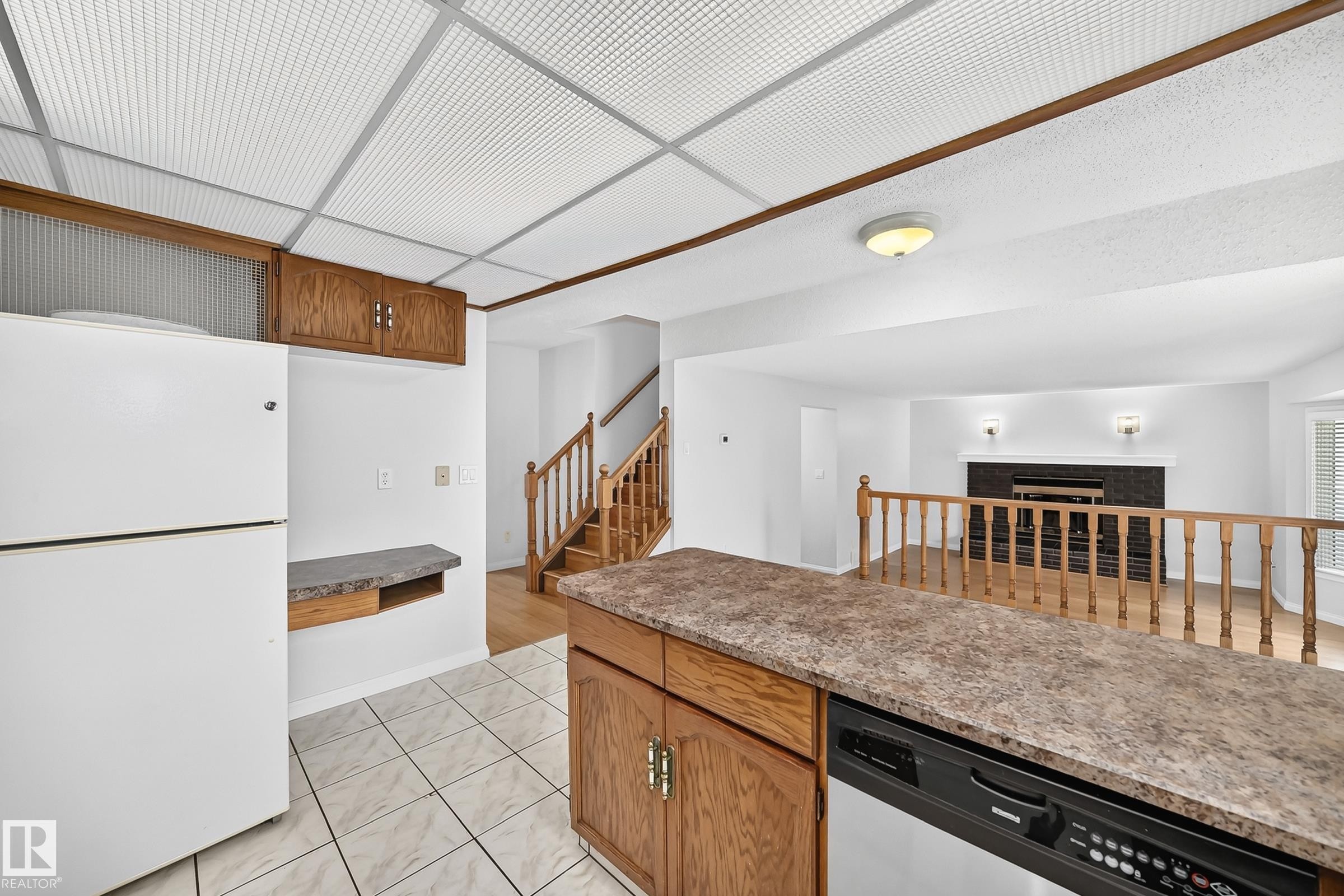 Kitchen area featuring white ceramic tile flooring and wood-finish cabinetry - 9843 188 Street, Edmonton, AB