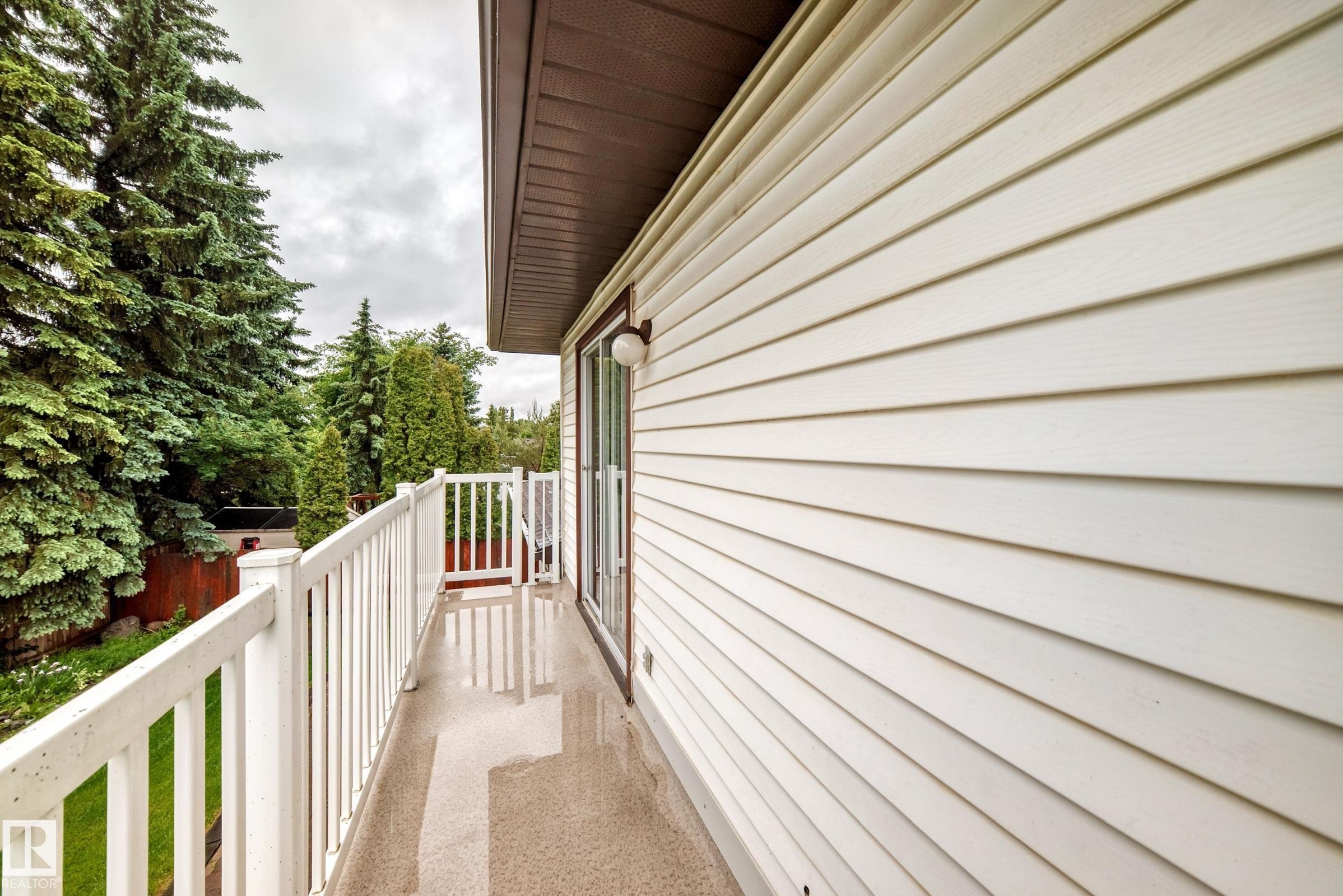 Exterior balcony featuring white railings, a sliding glass door, and a wall with horizontal siding - 9843 188 Street, Edmonton, AB