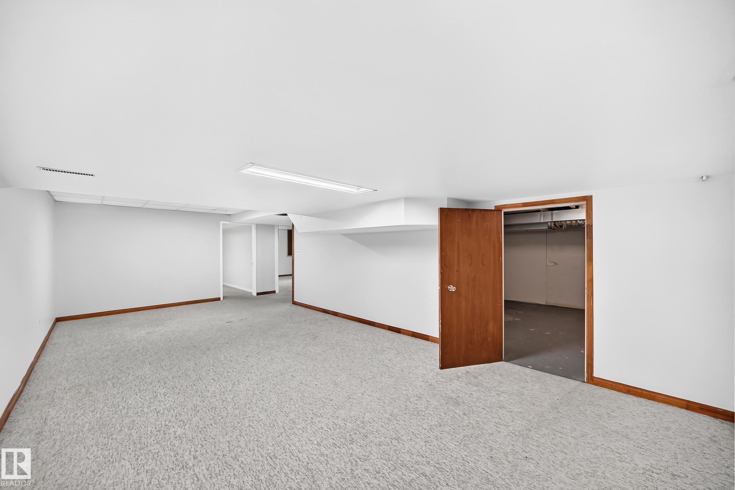 Spacious interior room featuring light-colored carpeting, white walls, and wood-finish baseboards - 9843 188 Street, Edmonton, AB